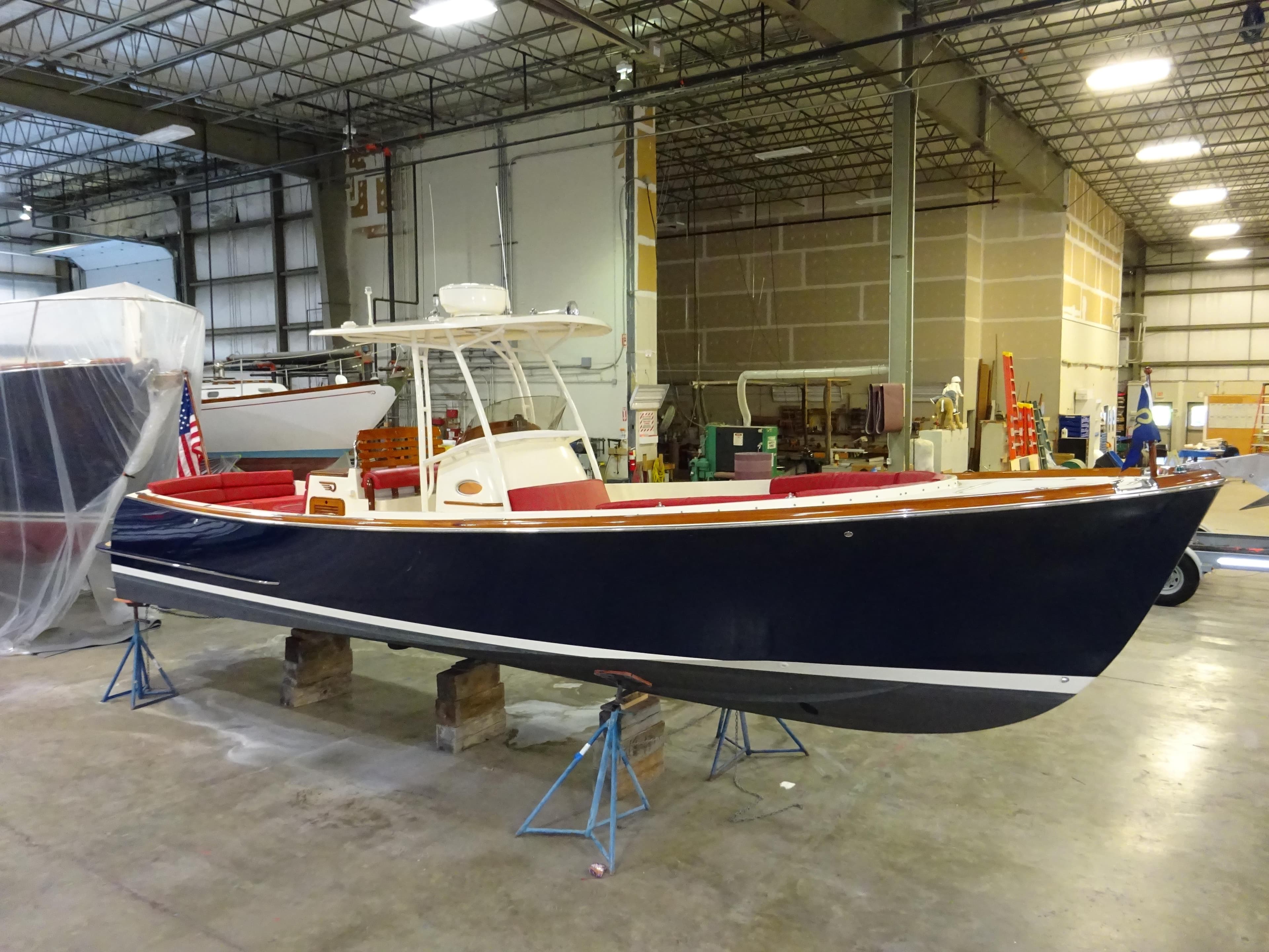 2007 Hinckley T29C boat in a warehouse, elevated on stands, with a sleek navy hull.