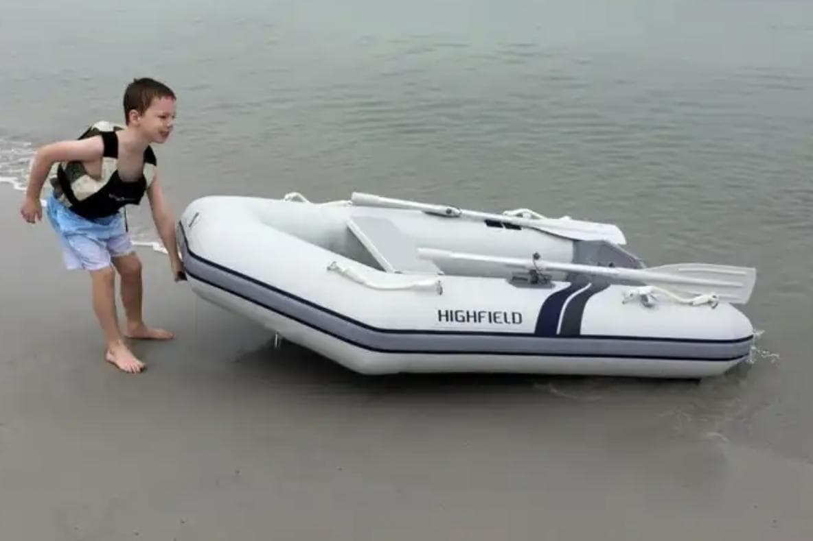 Child pulling Highfield Roll-Up 200 KAL inflatable boat on beach, 2025 model.