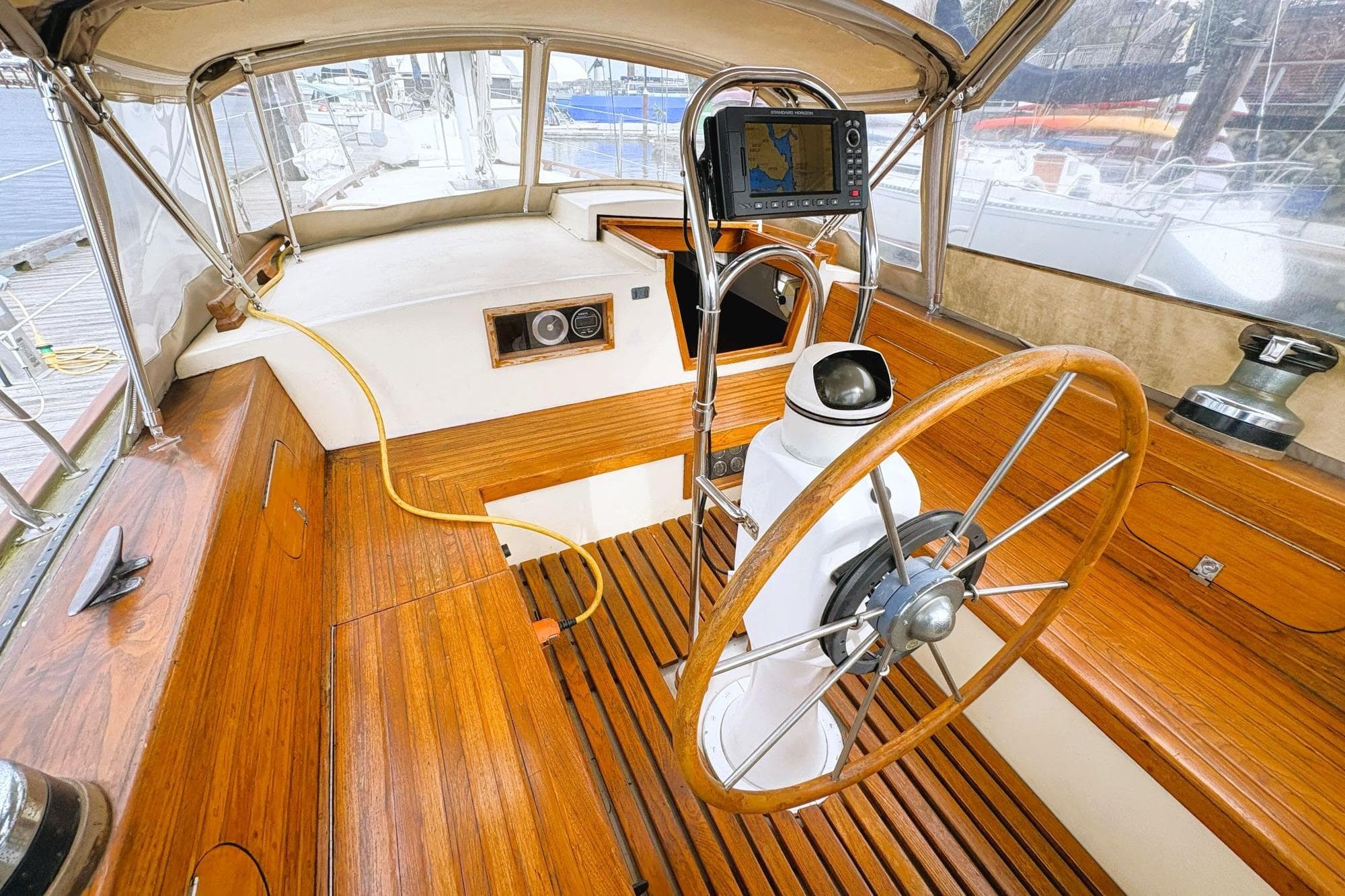 Vintage 1980 Discovery 42 sailboat cockpit with wooden wheel and navigation equipment.
