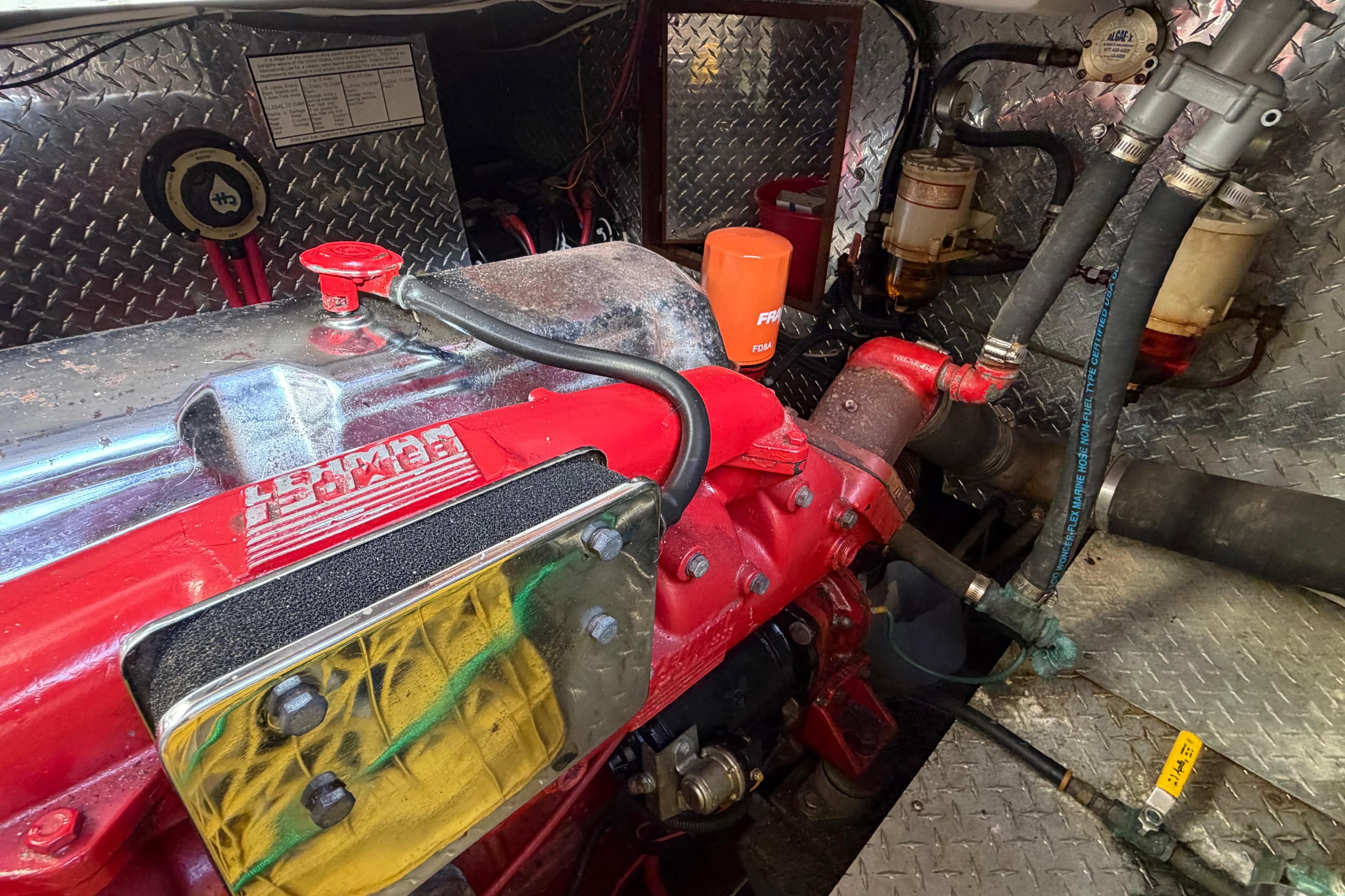 Engine compartment of a 1985 Albin 36 Trawler with red engine components and metal paneling.