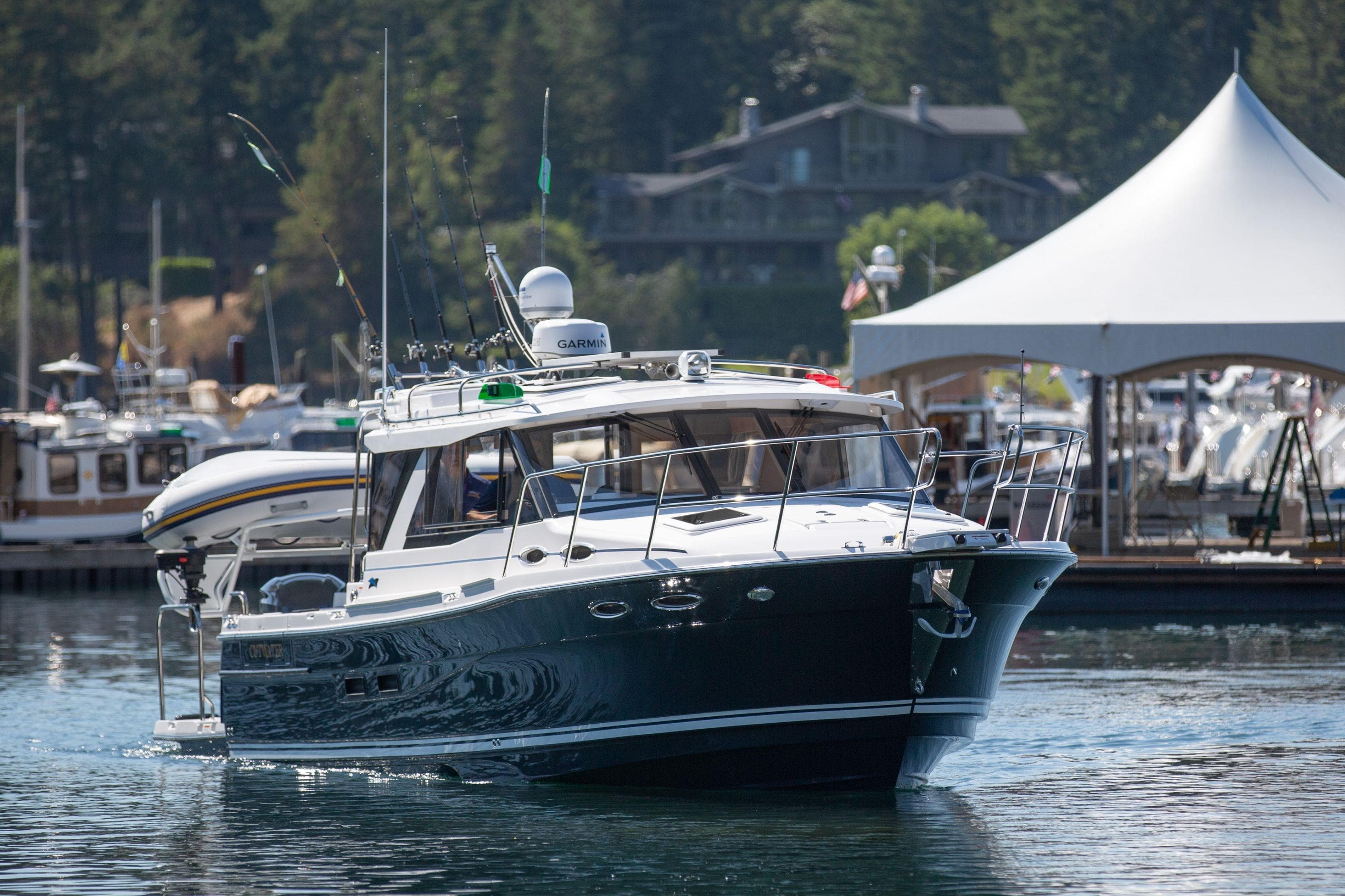 2026 Cutwater C-32 Coupe boat cruising in a marina with scenic background.