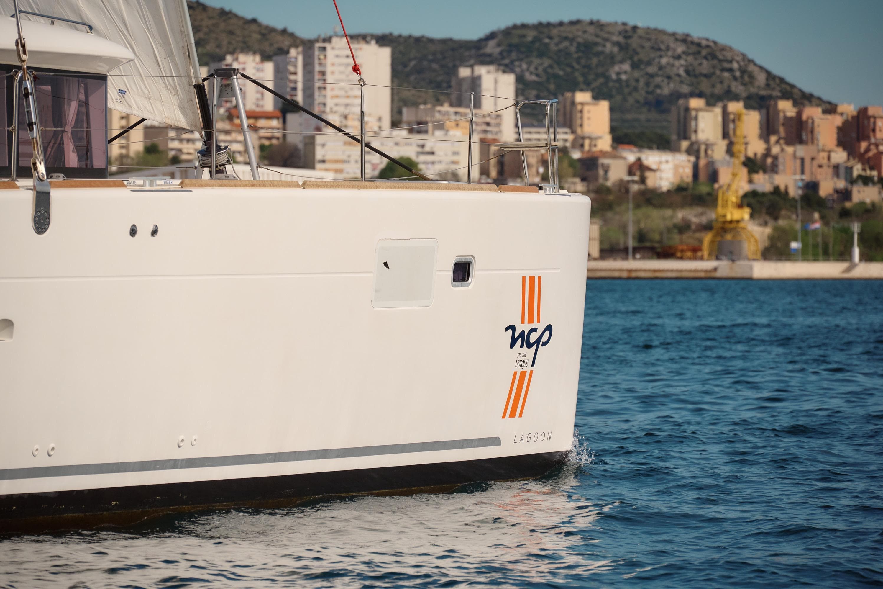 2018 Lagoon 450 catamaran docked near urban waterfront.