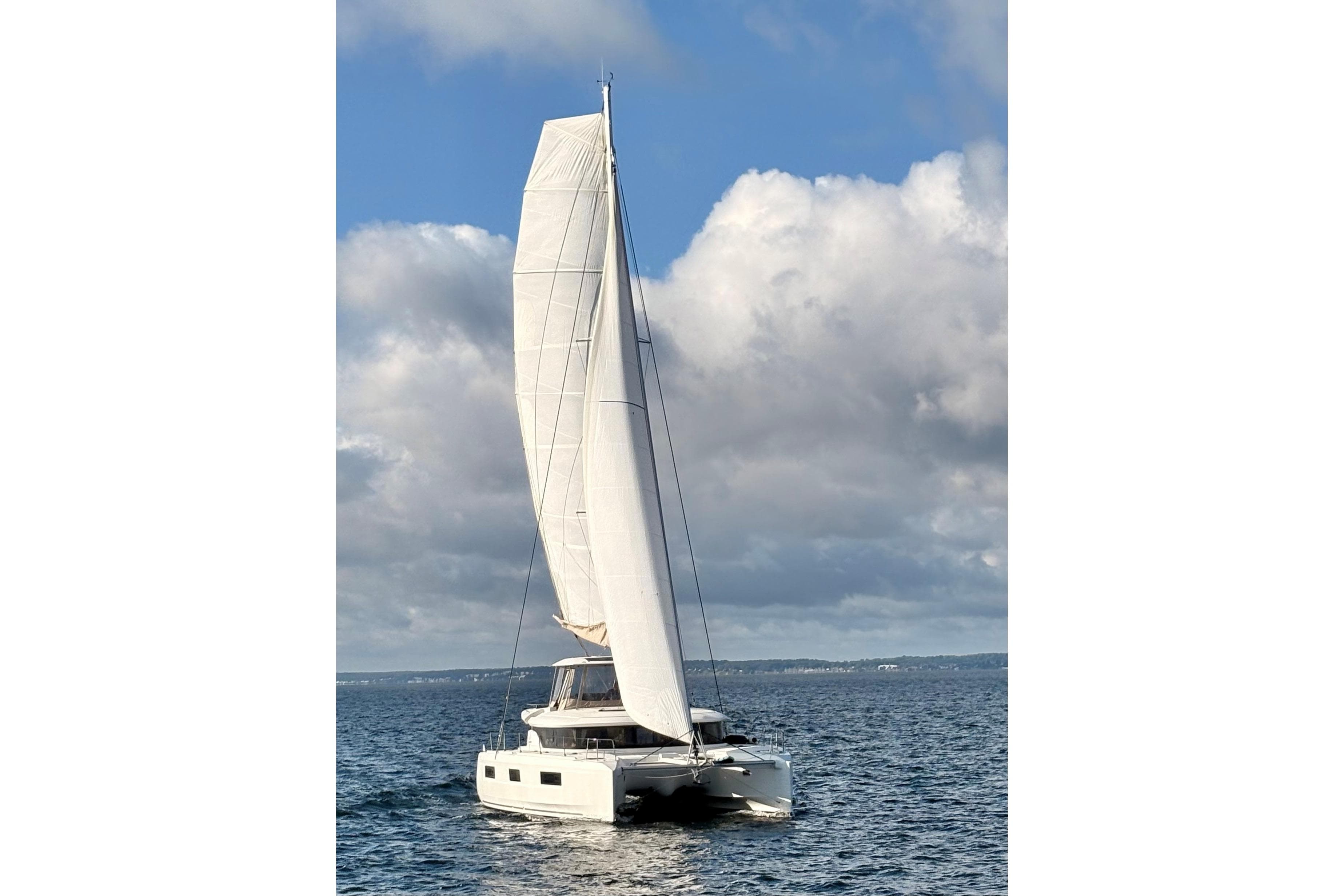 2021 Lagoon 46 catamaran sailing on open water under a cloudy sky.