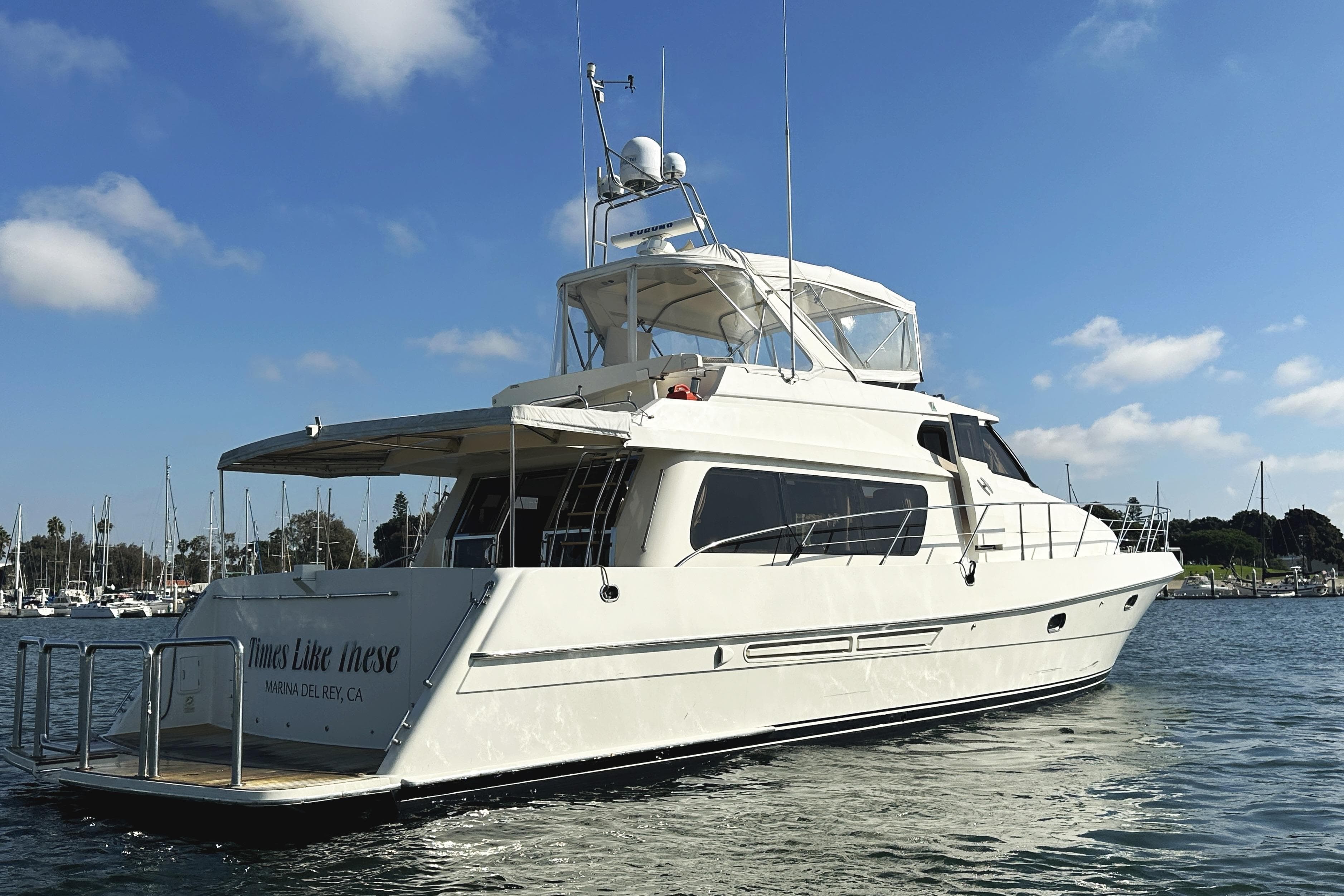 2004 McKinna 57 PHMY Widebody yacht with stabilization, docked in a marina under blue skies.