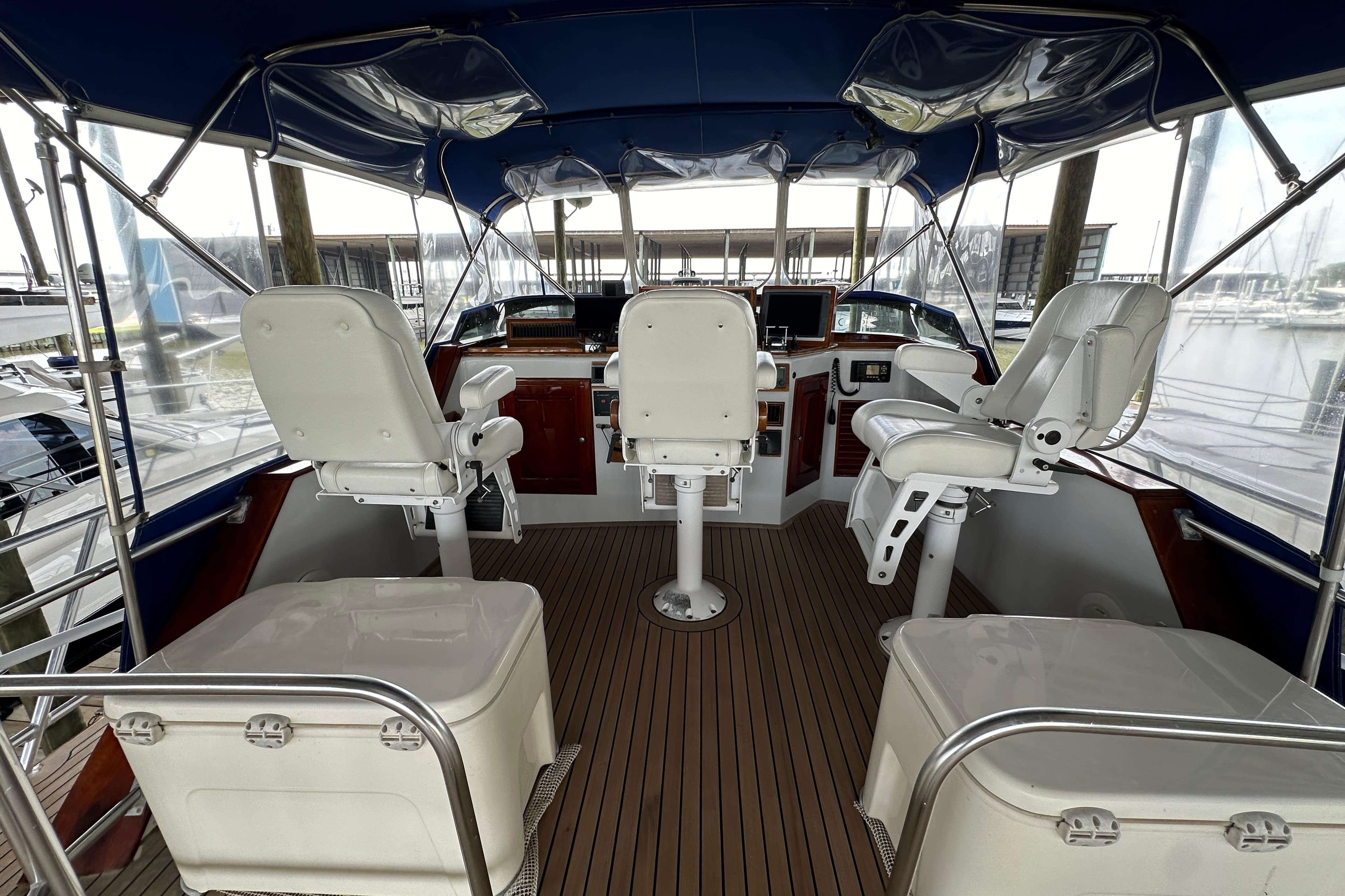 Interior view of a 1980 Bertram 58 Convertible yacht cockpit with white captain chairs.
