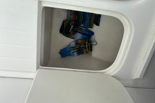 Storage compartment on a 1994 Sea Ray 240 boat with colorful items inside.