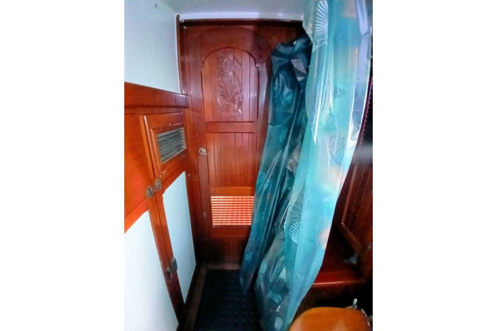 Interior of 1980 Hardin 45 sailboat with wooden door and blue curtain.