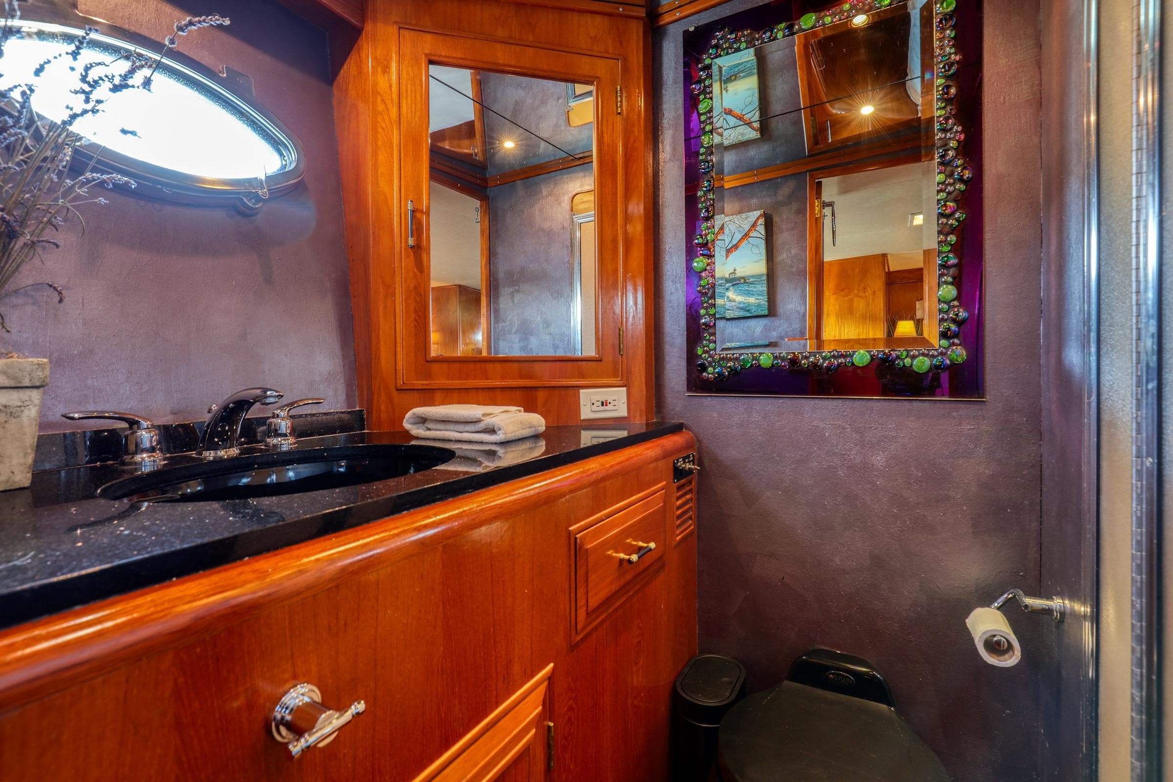Luxurious 1987 Ocean Alexander Motoryacht bathroom with elegant wood cabinetry and decorative mirror.