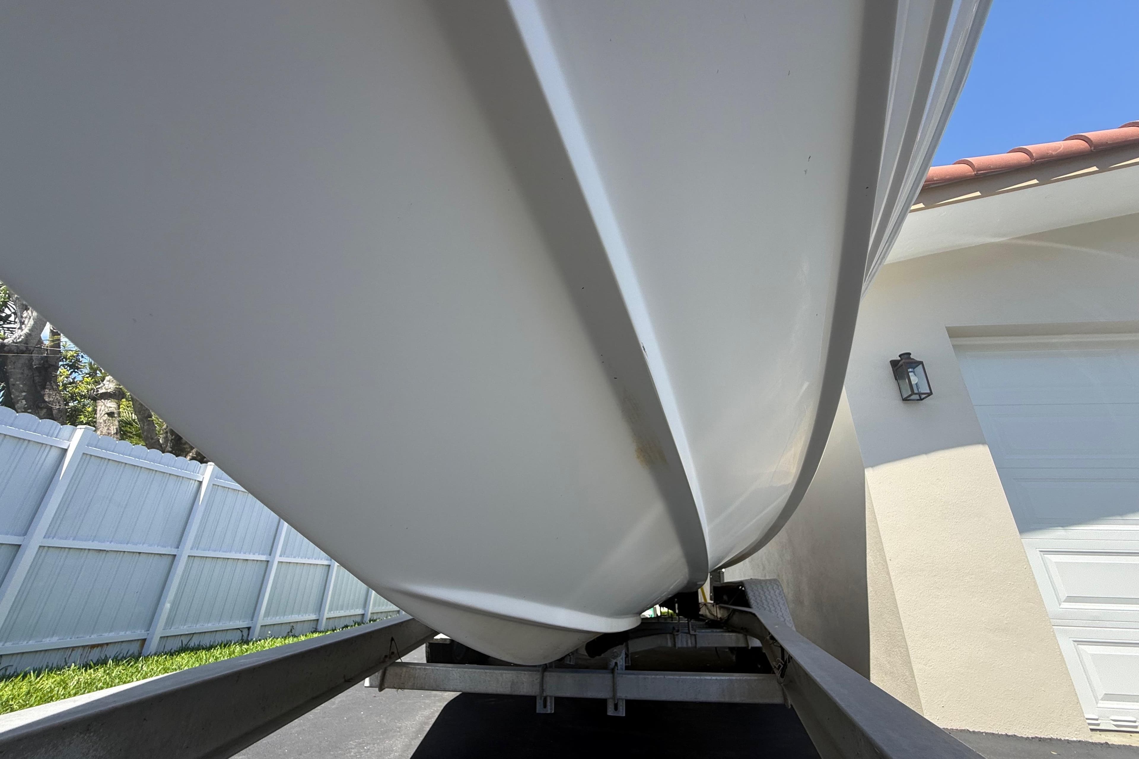 Underneath view of a 2015 Concept 27 boat on a trailer near a house.