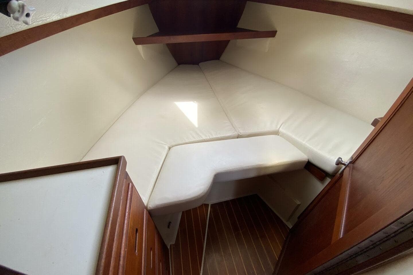 Interior cabin of a 1986 Catalina 34 sailboat with white cushions and wooden accents.