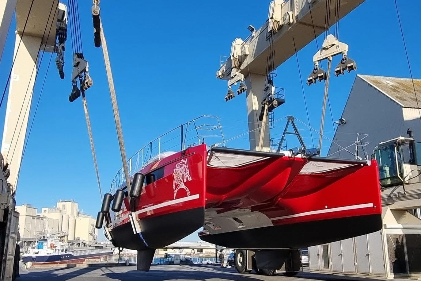 Red Privilege 510 catamaran being lifted by crane, 2022 model.