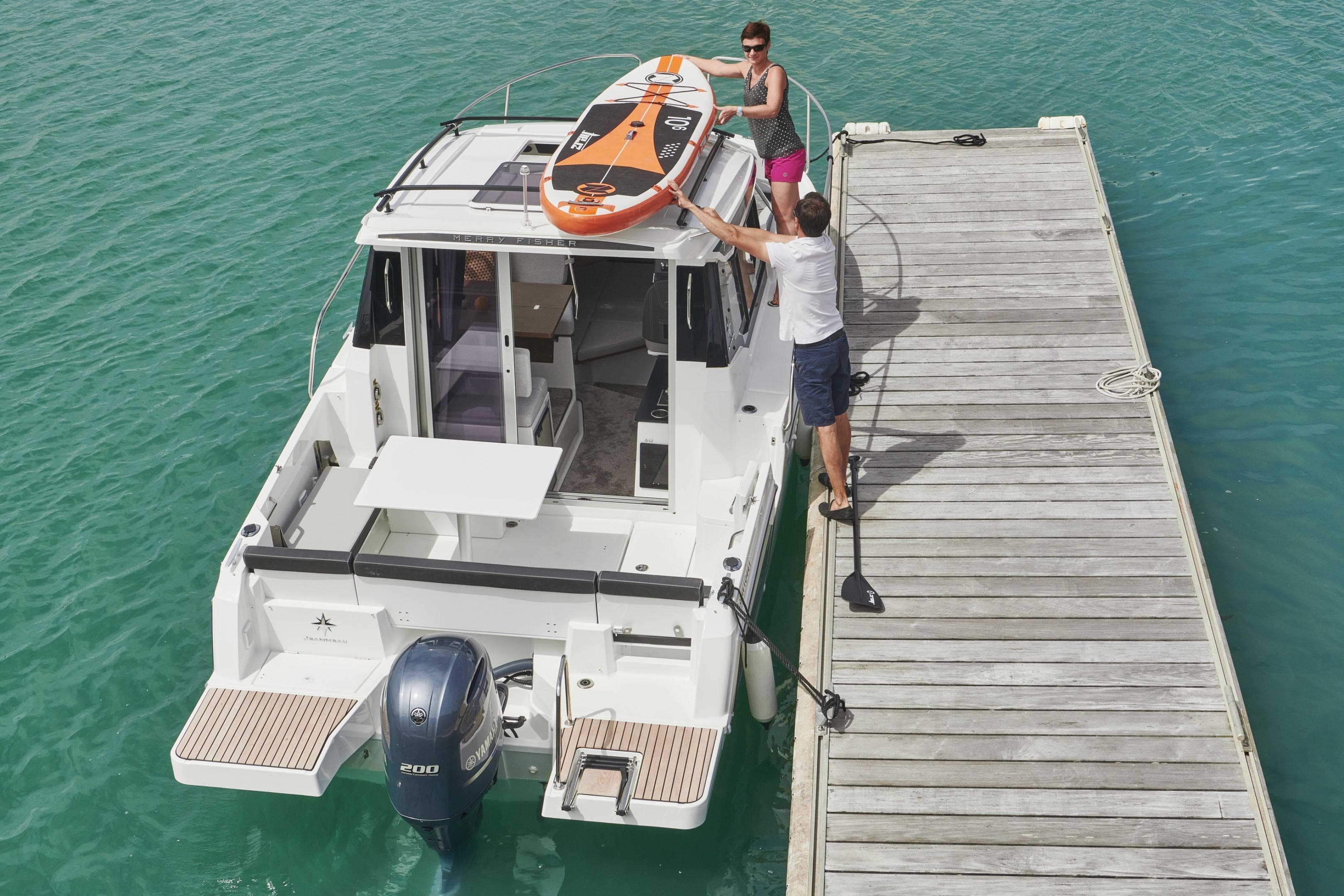 2026 Jeanneau NC 795 Series 2 docked, with paddleboard on roof, in turquoise water.