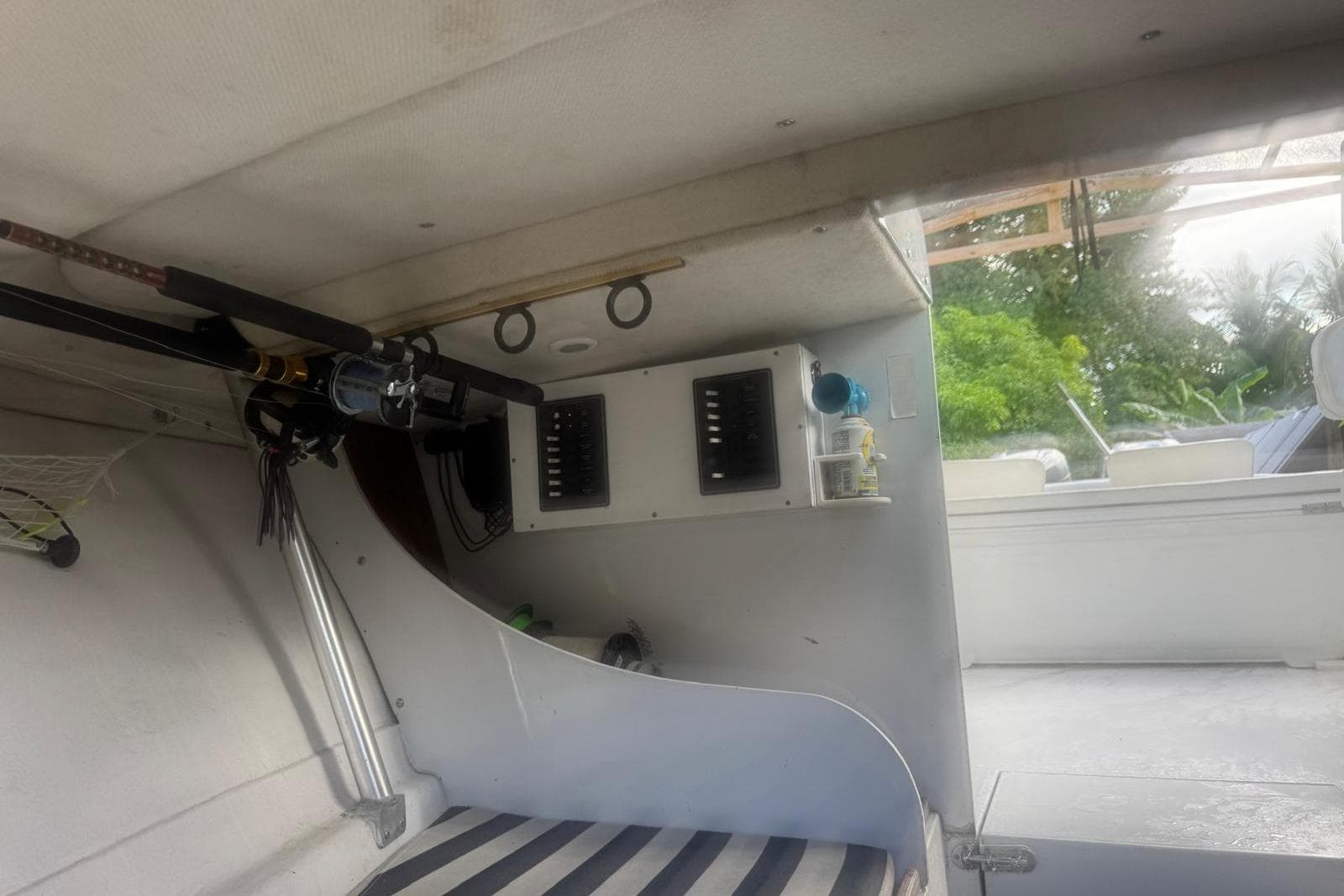Interior of a 1962 Bertram 25 Moppie boat with fishing rods and control panel.