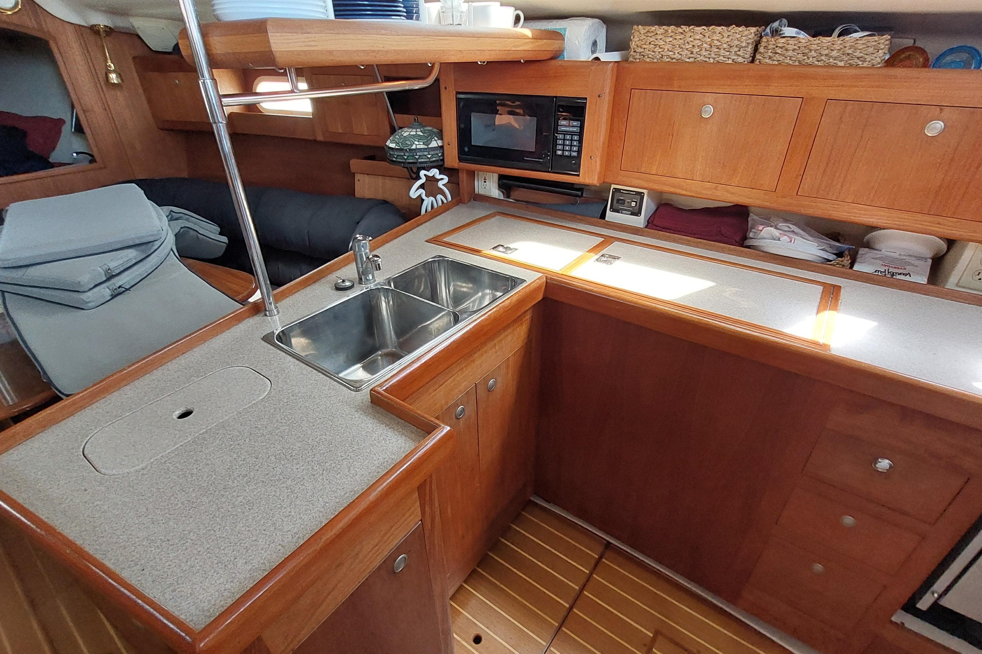 Interior of a 2002 Hunter 380 sailboat kitchen with wooden cabinetry and dual sink.