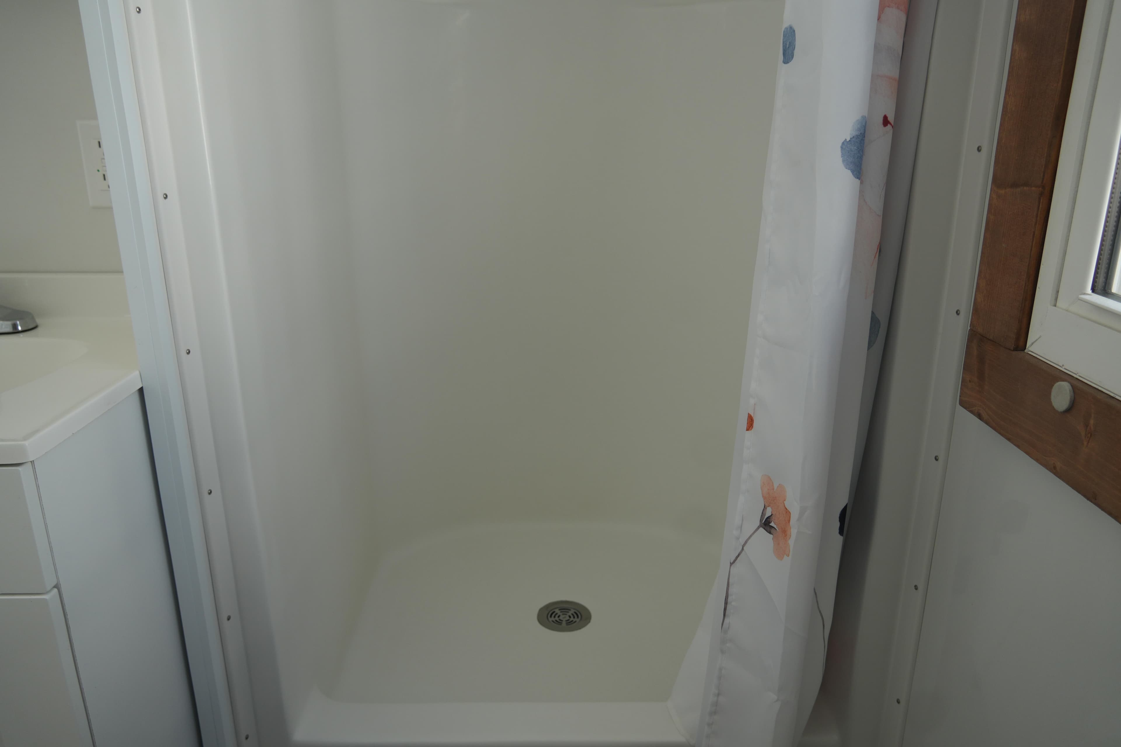 Shower area in 2024 Catamaran Aqua Lodge with floral curtain and white interior.