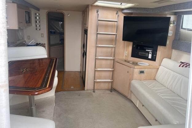 Interior of 1999 Carver Mariner 350 yacht with seating, table, and entertainment system.