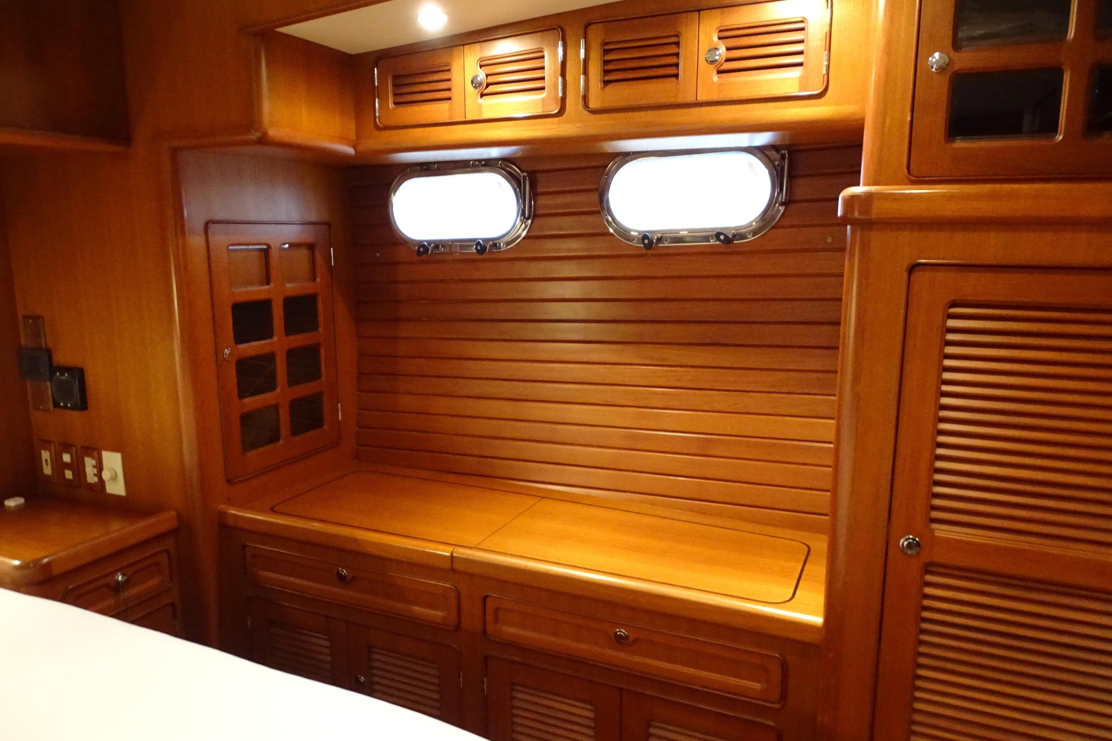 Luxurious wooden interior of a 2004 Selene 53 yacht cabin with portholes and storage.