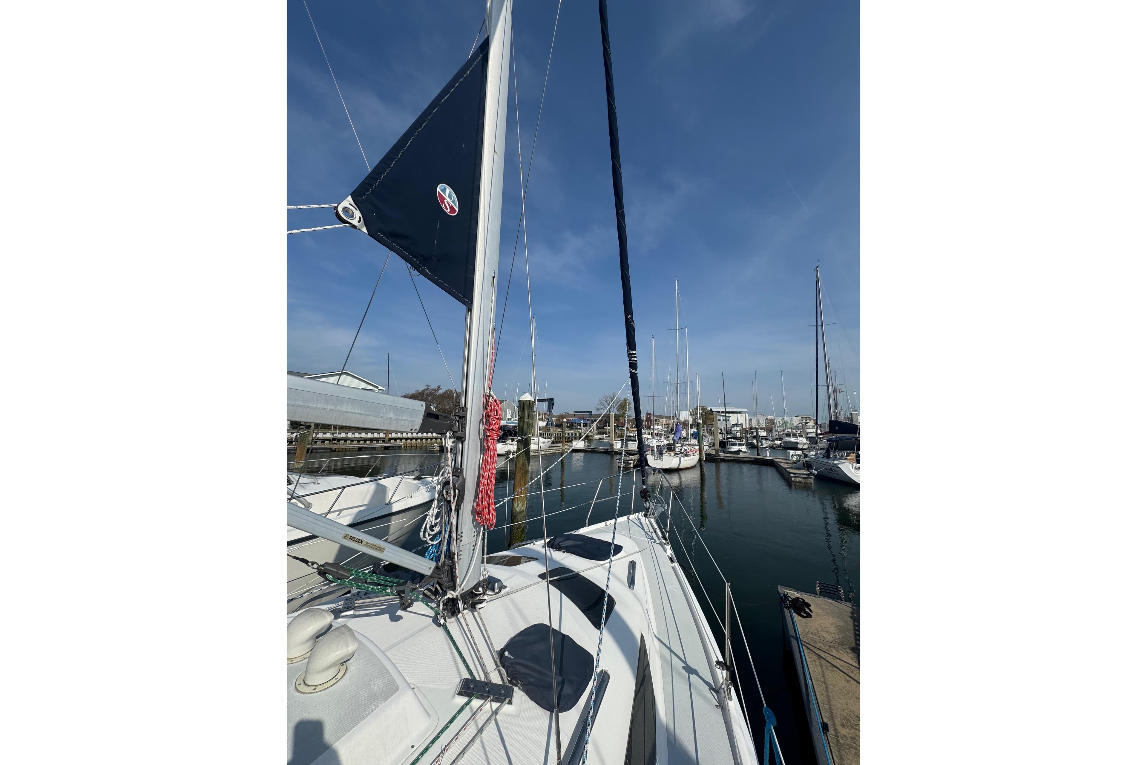 Sailboat Hunter 326, 2002 model, docked at marina under clear blue sky.