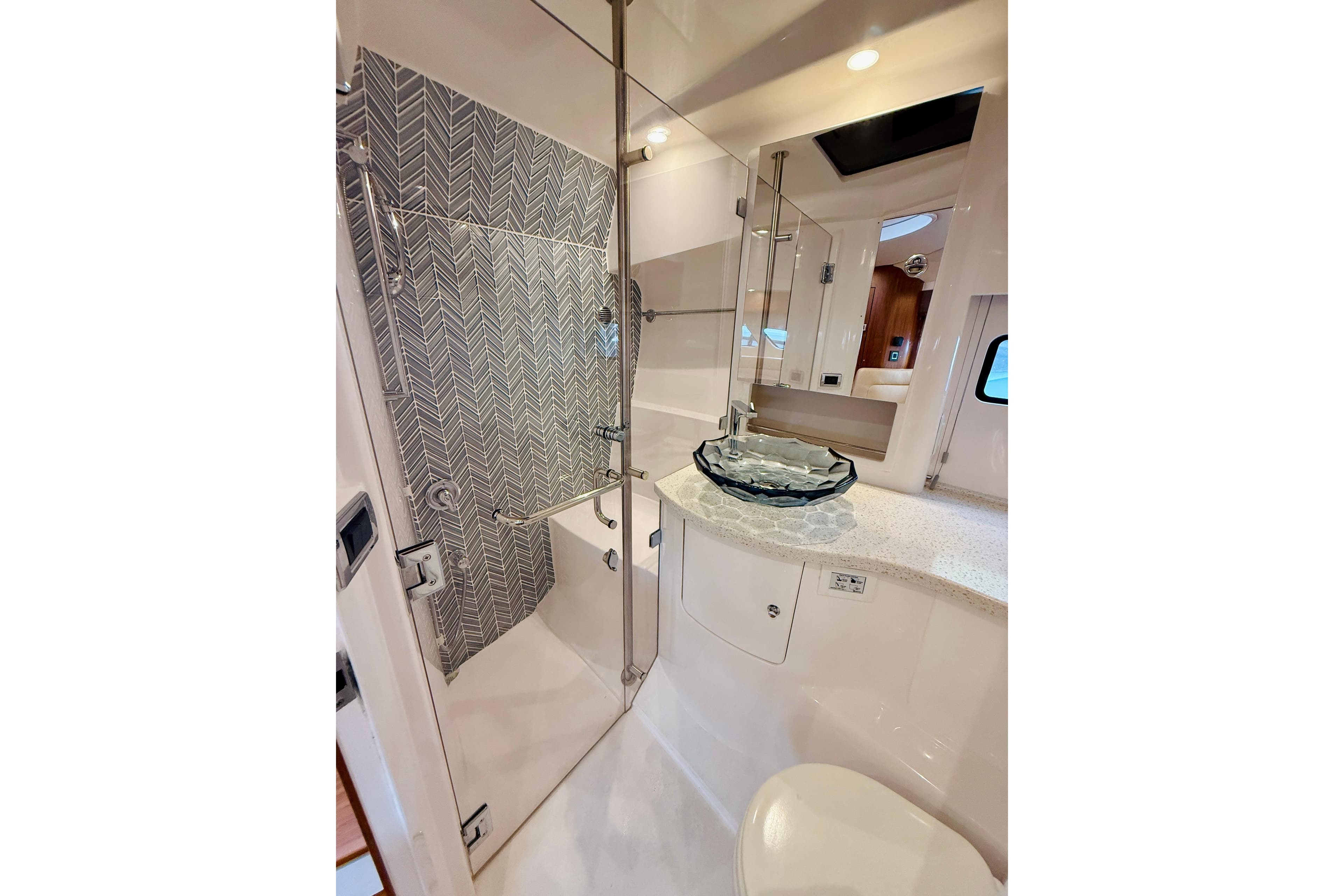 Luxurious bathroom in 2021 Intrepid 410 Evolution yacht with glass sink and modern shower.