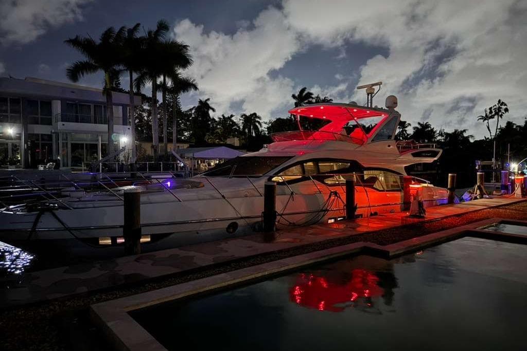 Luxurious 2014 Azimut 64 yacht docked at night, illuminated by red lights.
