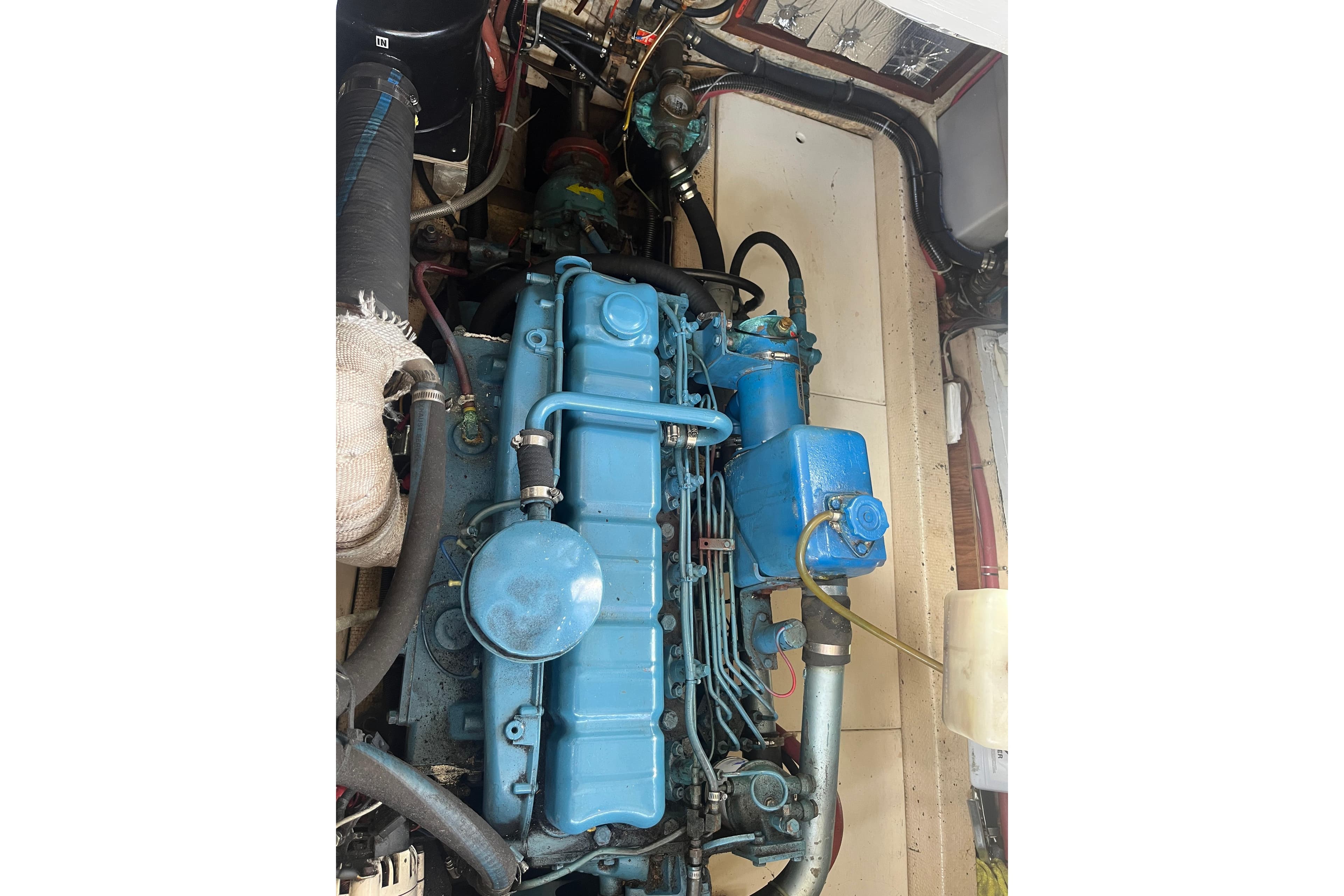 Engine of a 1974 DeFever 40 boat, showcasing blue components and surrounding machinery.