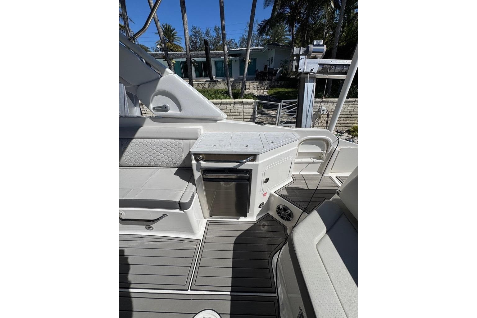2025 Sea Ray SDX 290 Outboard interior with seating and kitchenette, docked near palm trees.