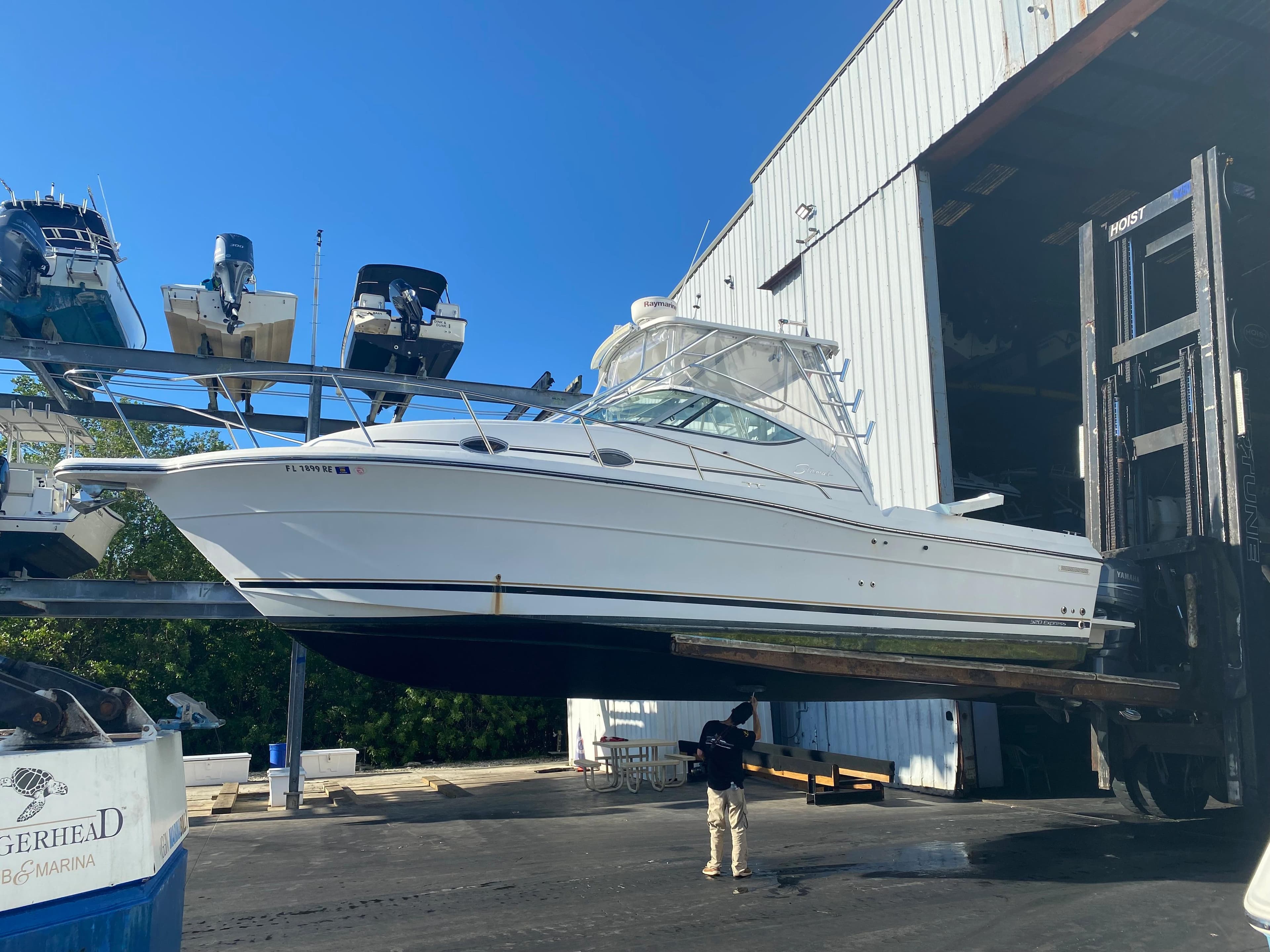 2006 Stamas 320 Express boat lifted near a large warehouse.