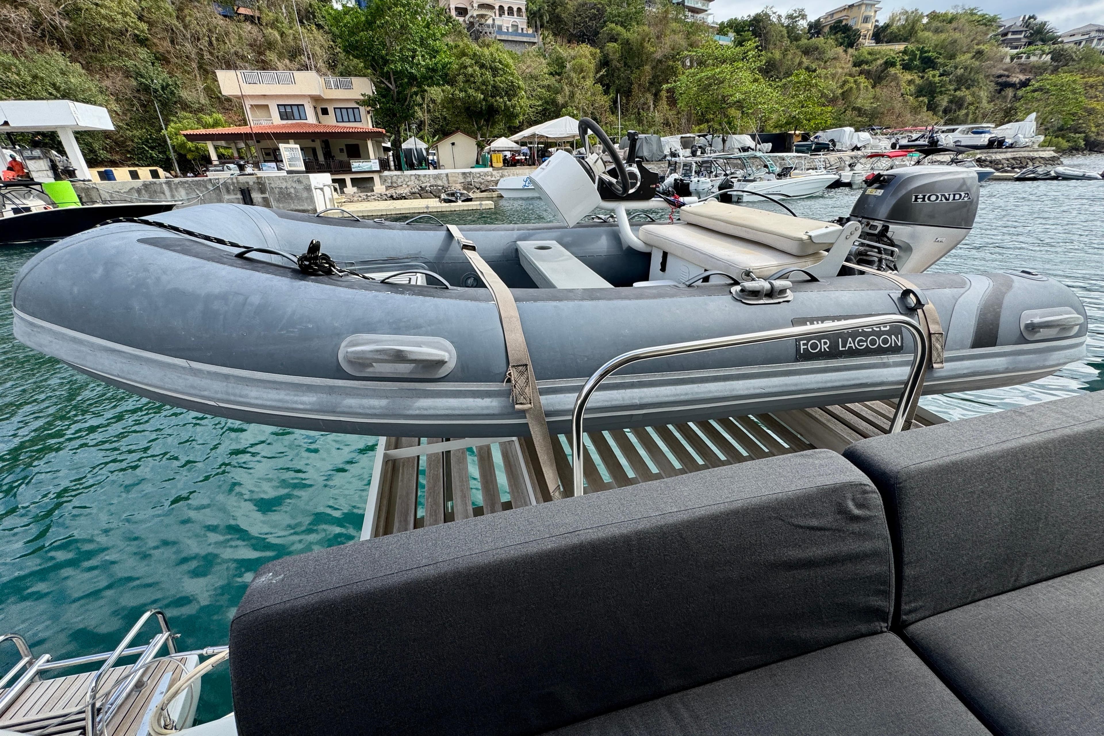 Gray inflatable boat with Honda motor, docked near a scenic waterfront, labeled "For Lagoon."