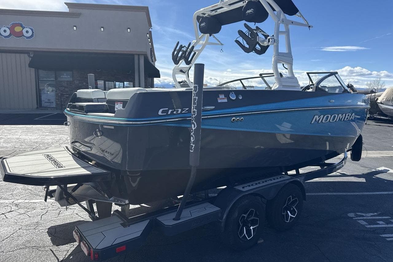 2025 Moomba Craz boat on trailer, parked outdoors, showcasing sleek design and vibrant colors.