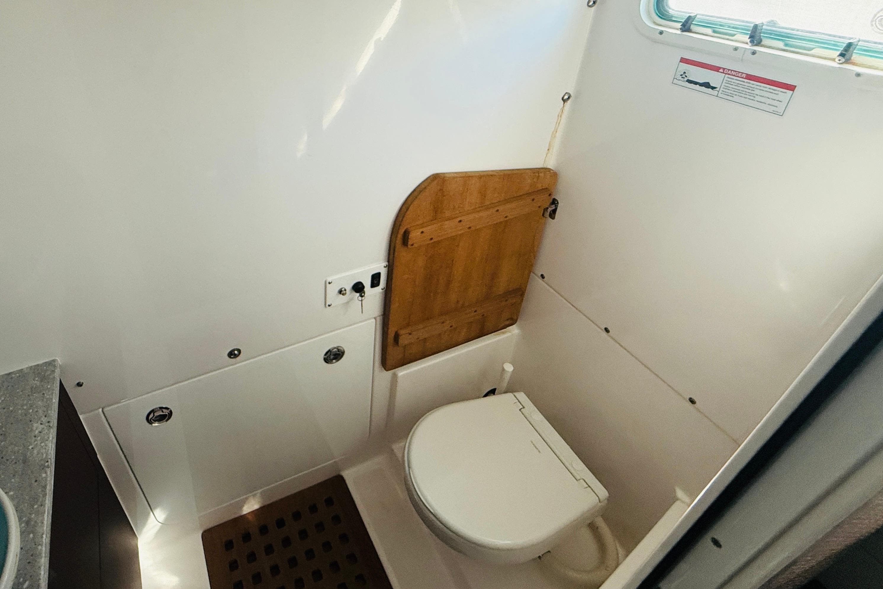 Interior of 2021 Everglades 395 Center Console boat bathroom with toilet and wooden accents.