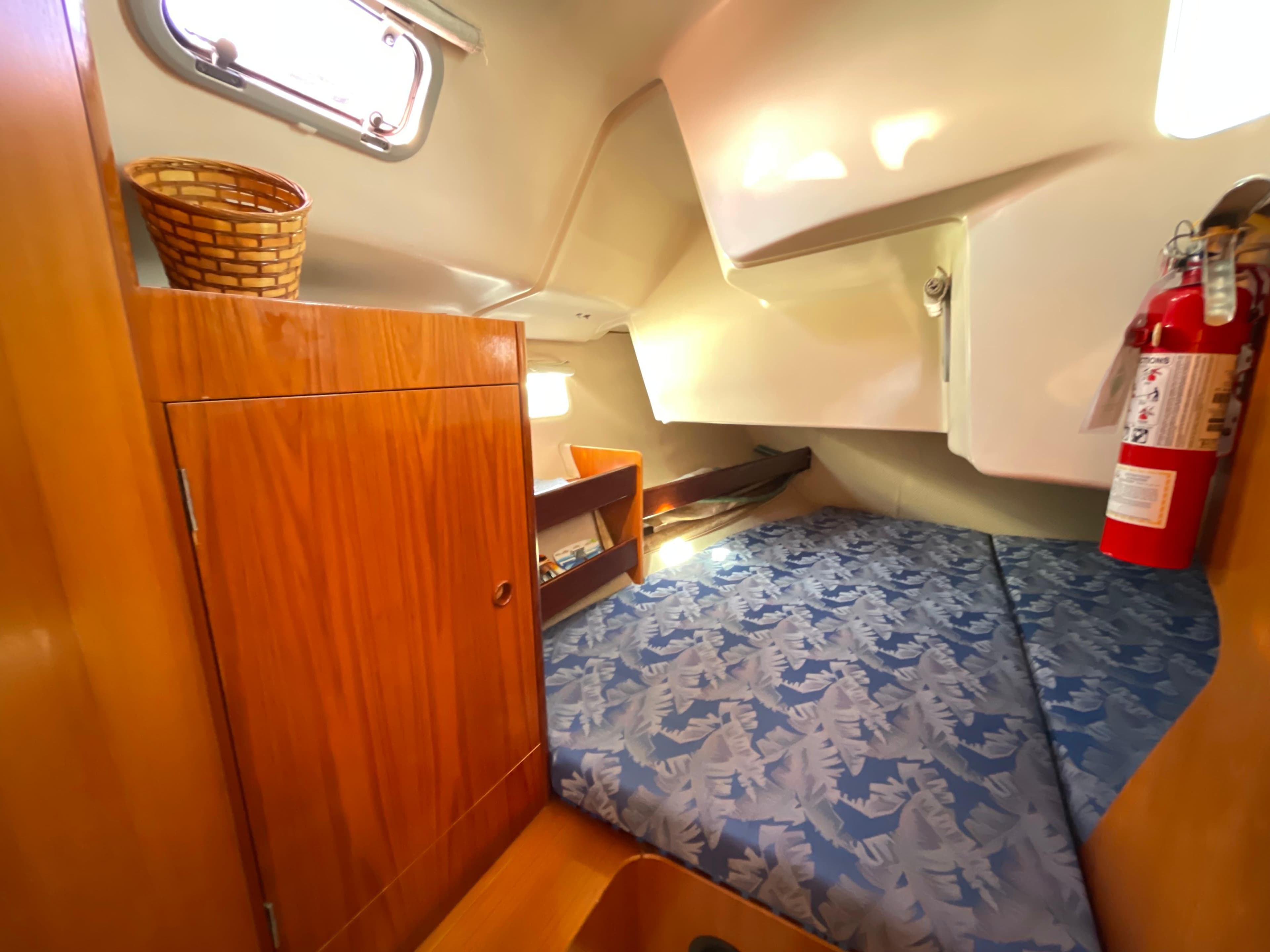 Cozy cabin interior of a 1994 Beneteau 352 sailboat with wooden cabinetry and patterned bedding.