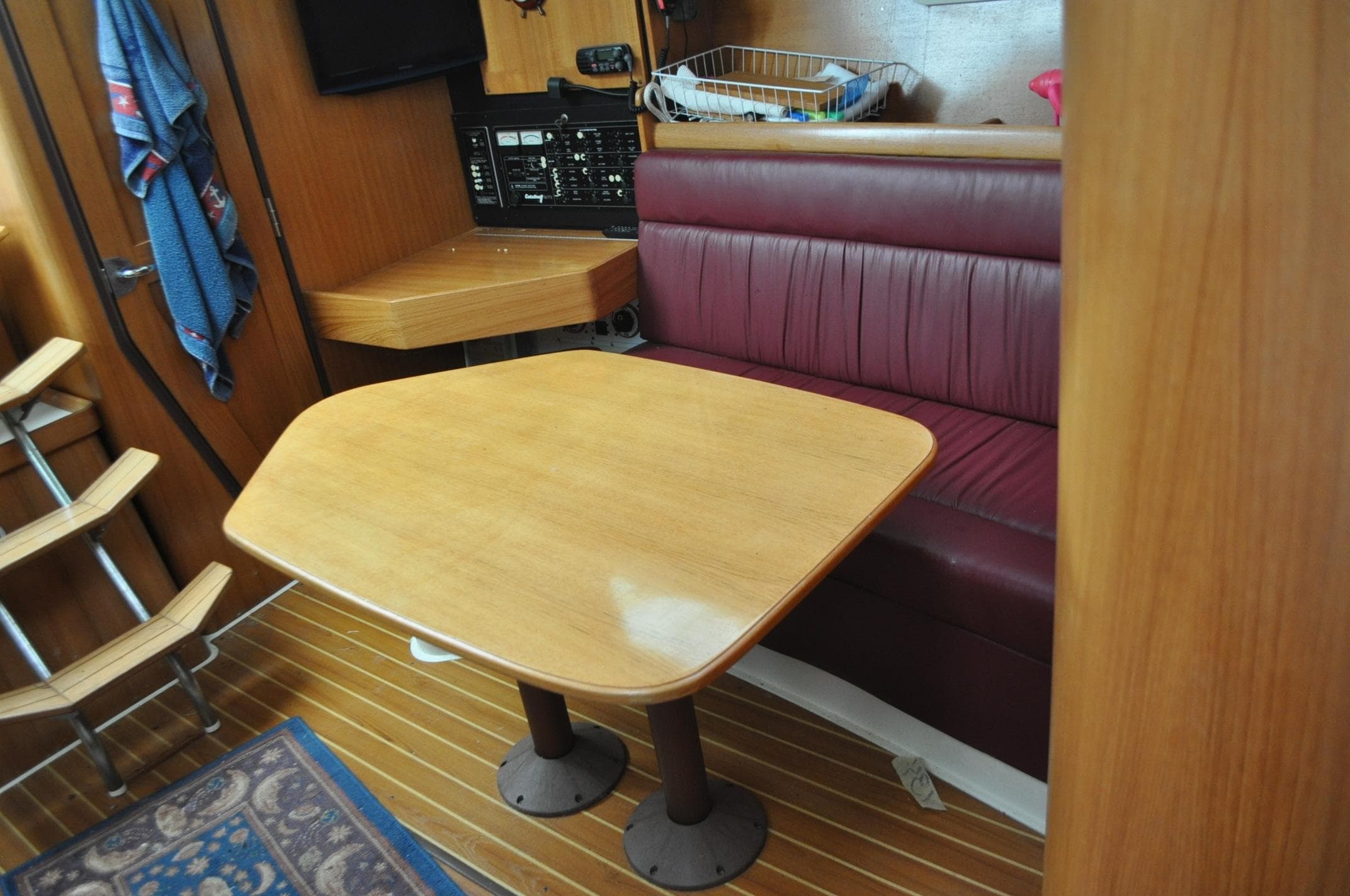 Interior of 2004 Catalina 350 MkII sailboat with wooden table and maroon seating.