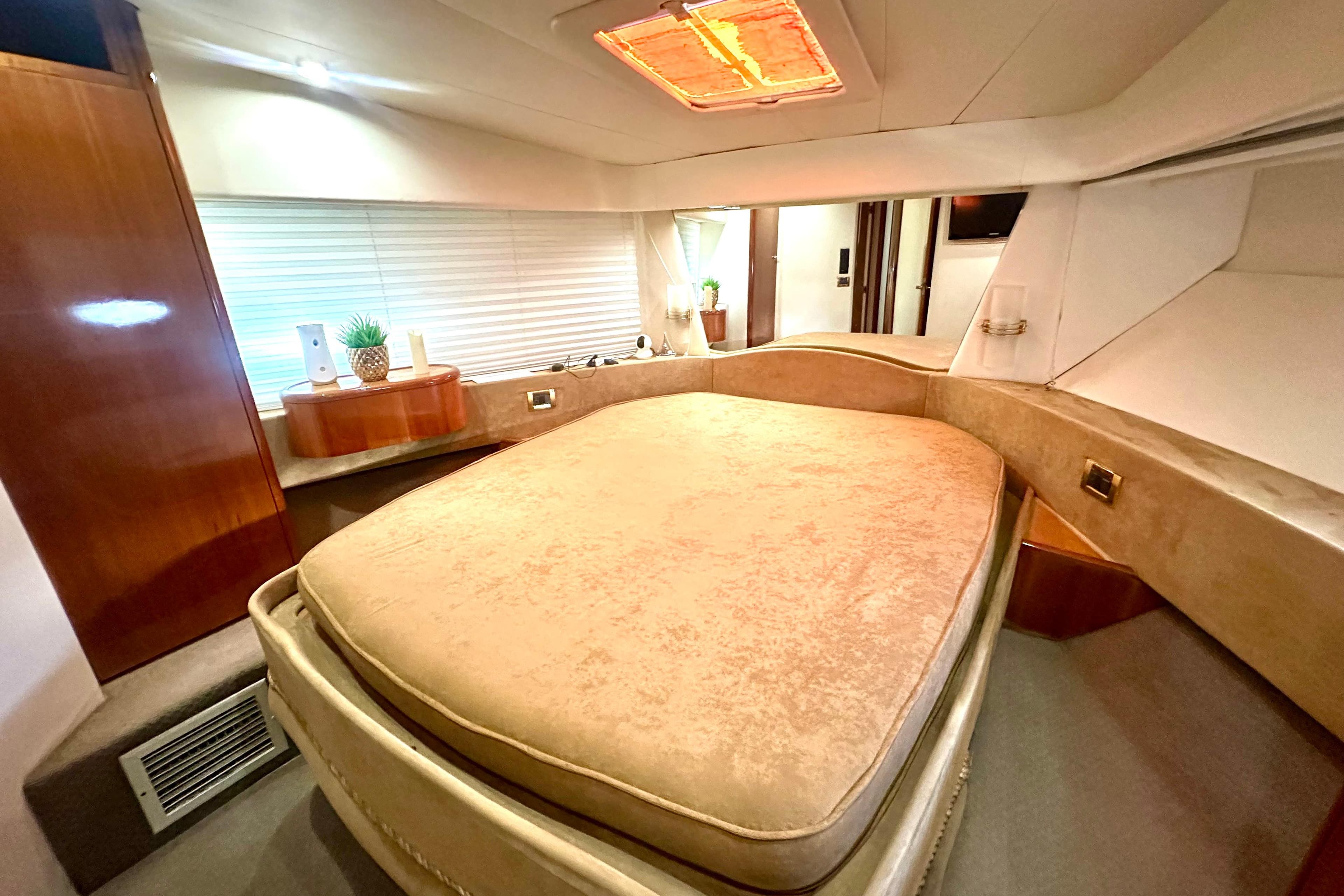 Luxurious bedroom interior of a 1999 Azimut 58 yacht with elegant furnishings.