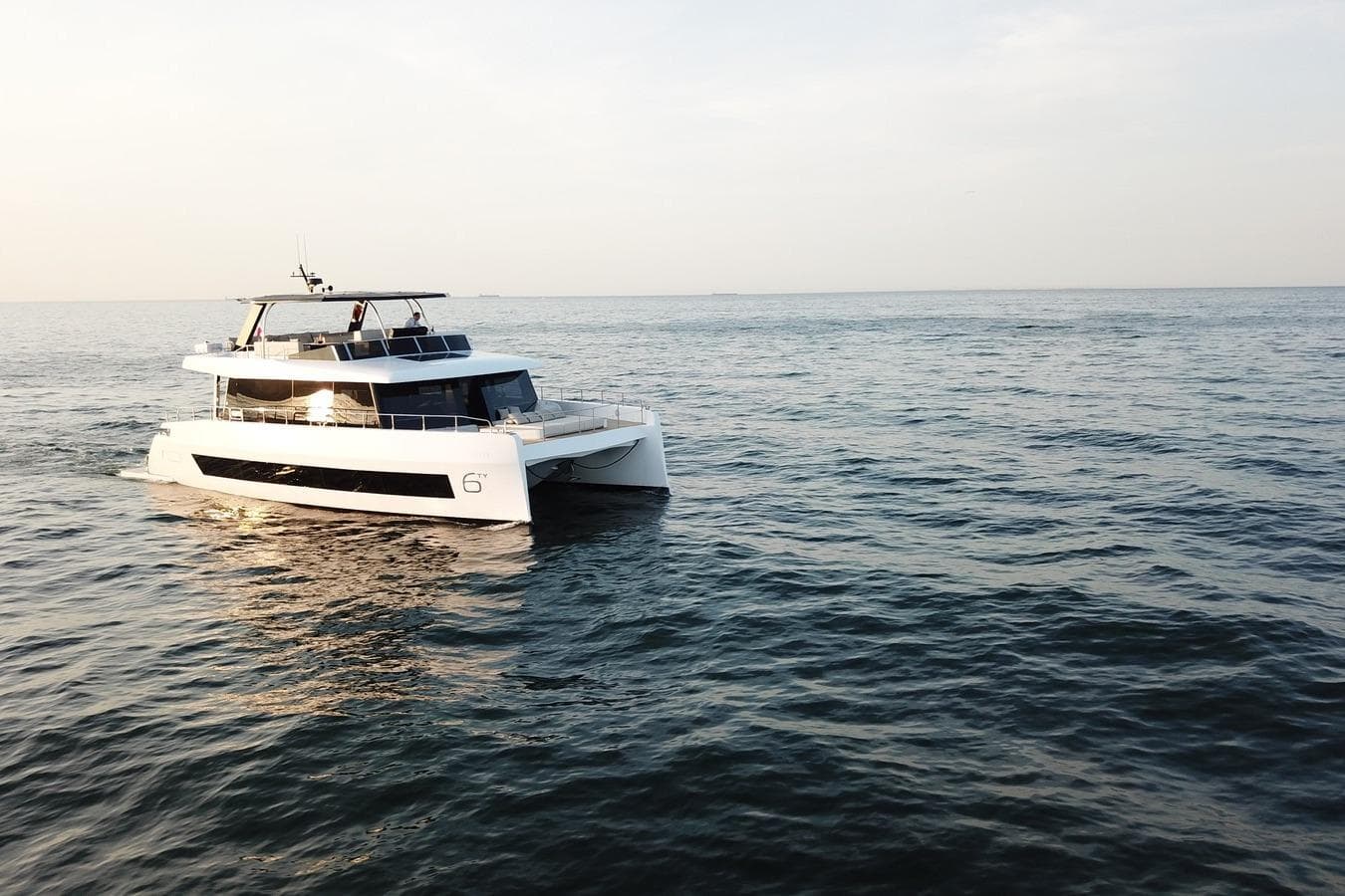 2026 Moon Yachts 6ty sailing on calm ocean waters at sunset.