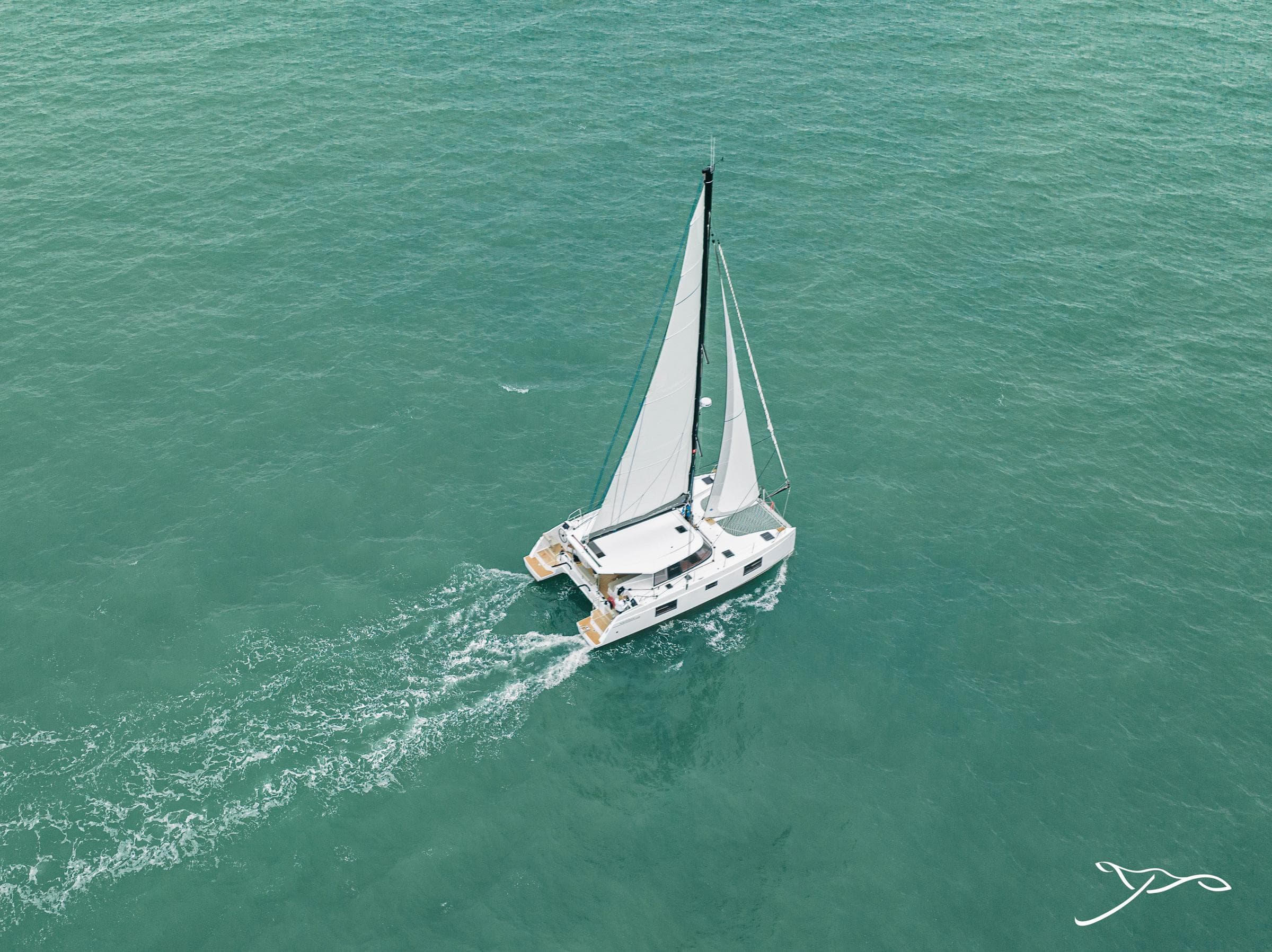 Aerial view of 2025 Nautitech 40 Open catamaran sailing on turquoise waters.