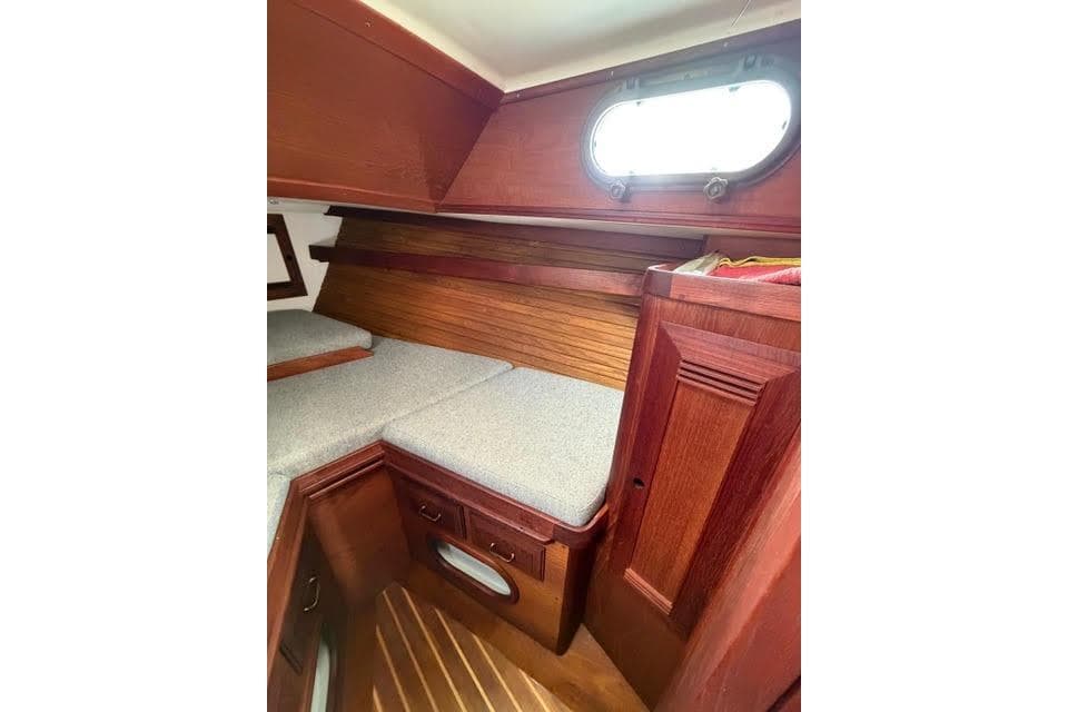 1985 Cape Dory Cutter cabin interior with wooden finish and cushioned seating.