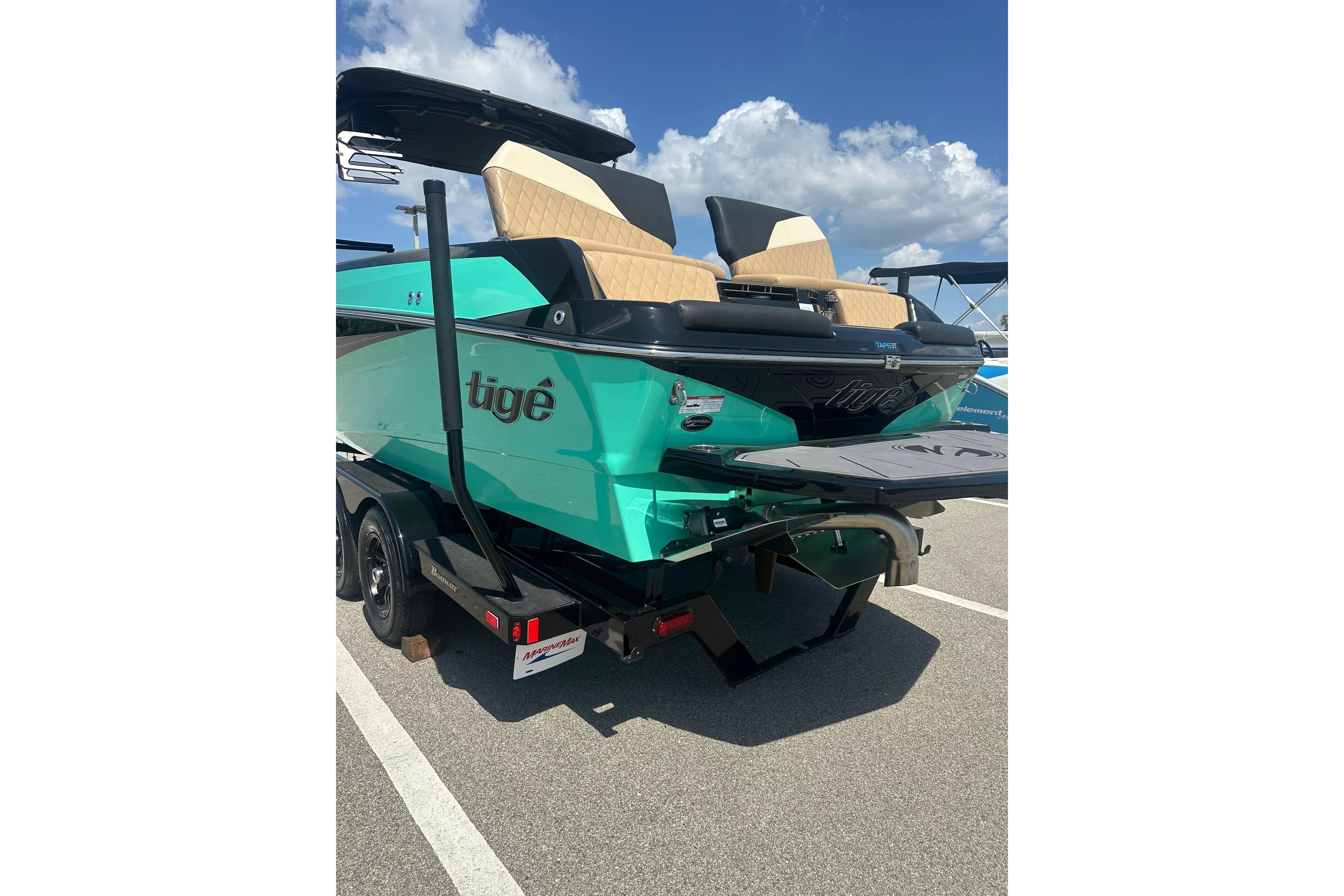2023 Tigé 23ZX boat in vibrant teal, parked on a trailer under a blue sky.