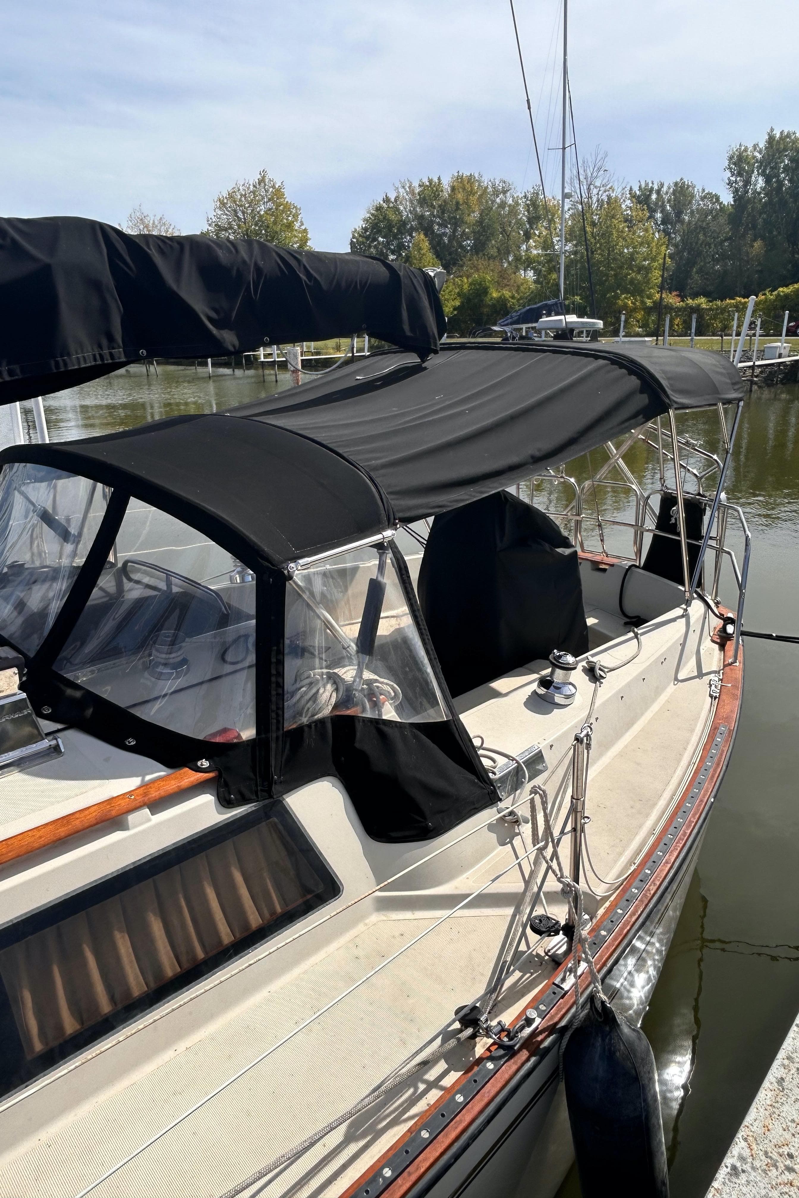 1982 S2 11.0 A sailboat with black canopy docked in a marina.
