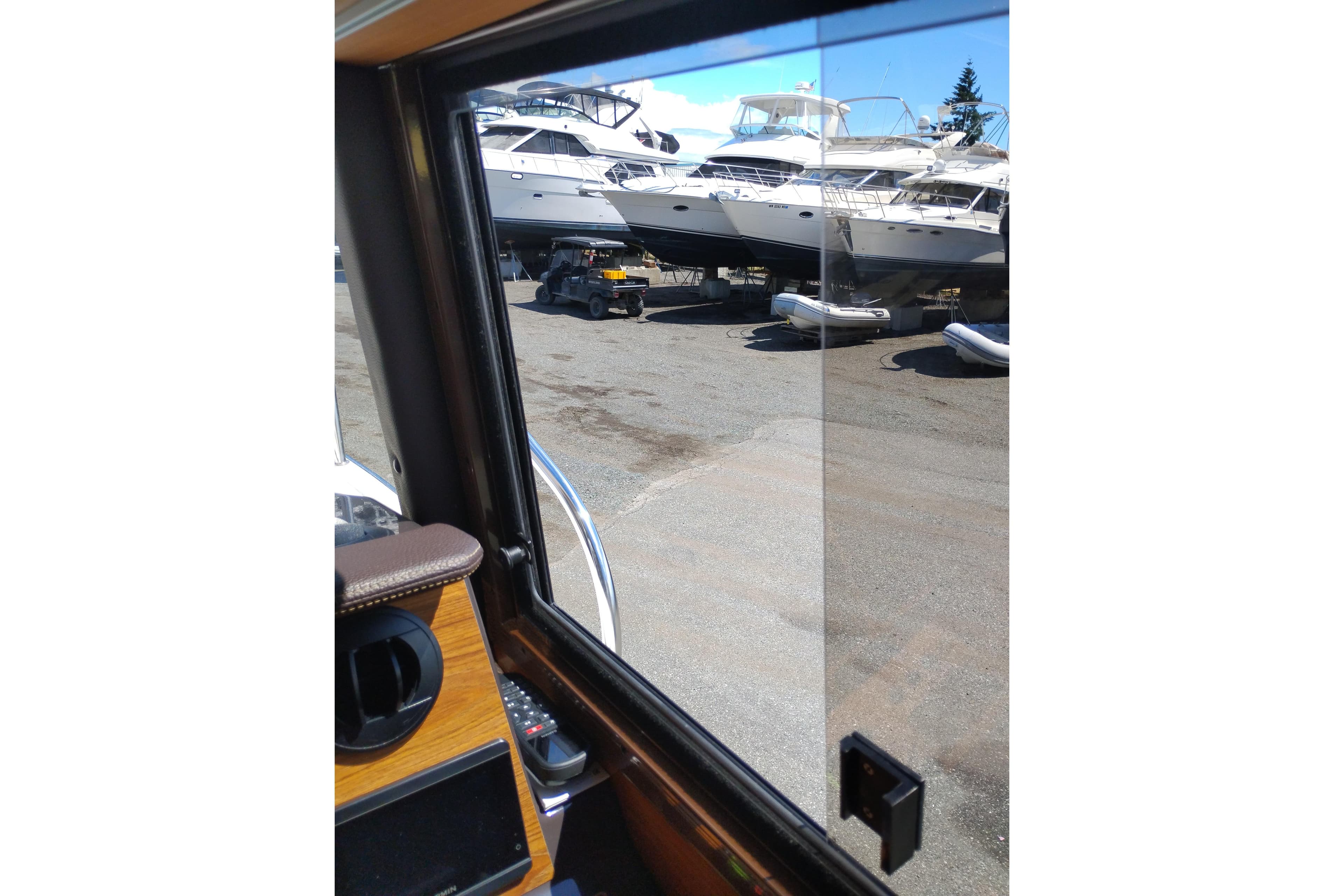 View from inside a 2024 Ranger Tugs R-27, overlooking parked boats and a utility vehicle.
