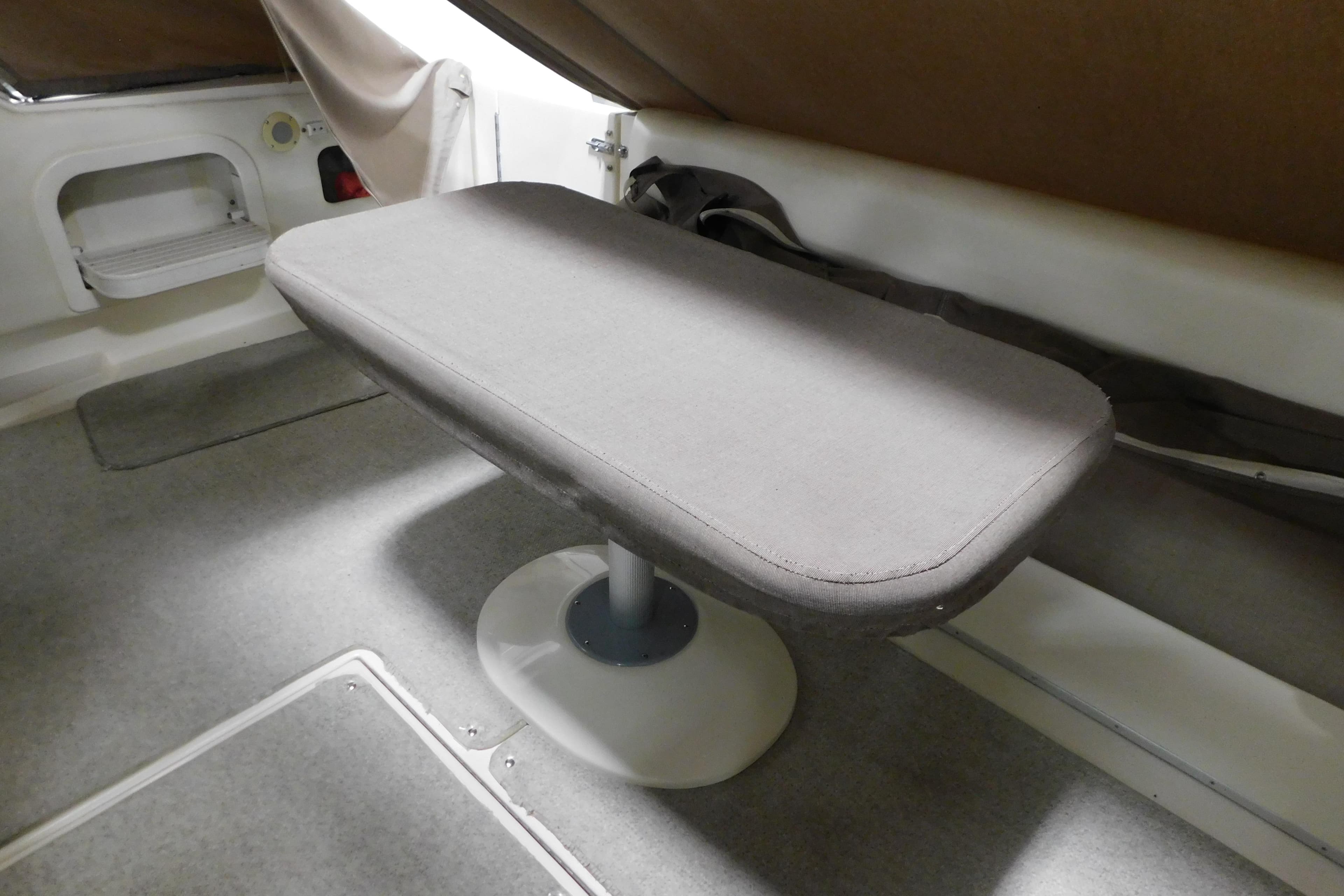Interior table on 1999 Sea Ray 500 Sundancer yacht, featuring gray upholstery and carpeted flooring.