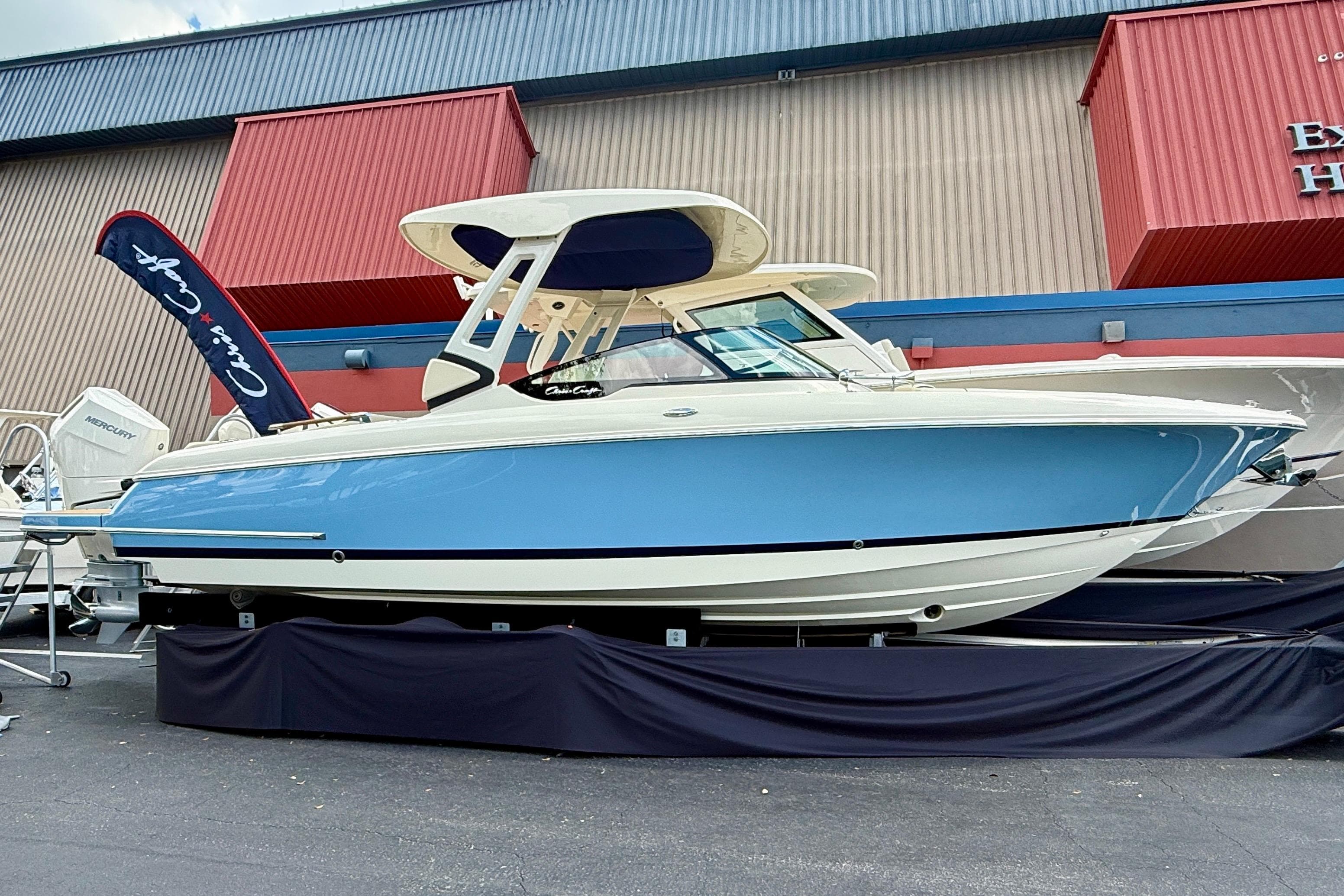 2026 Chris-Craft Sportster 28 boat displayed outdoors, featuring a sleek blue and white design.
