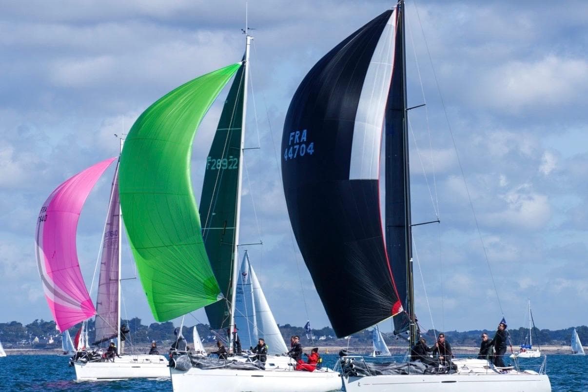 Sailboats racing with colorful spinnakers, featuring a 2000 Beneteau First 31.7 model.