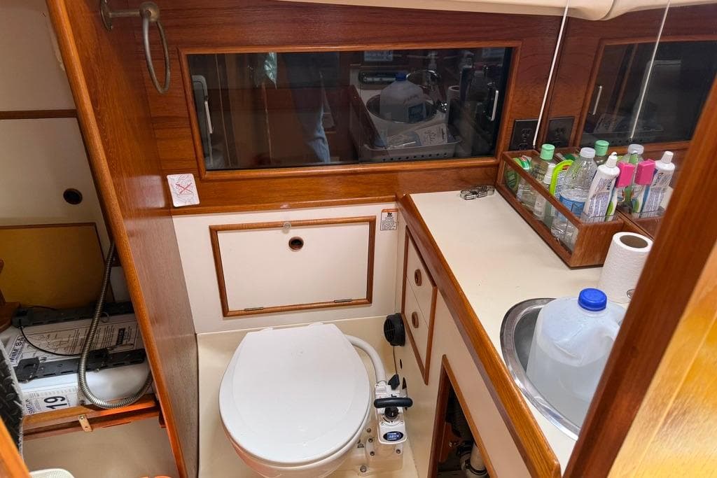1986 Nonsuch Ultra 30 yacht bathroom with wooden cabinetry and essential toiletries.