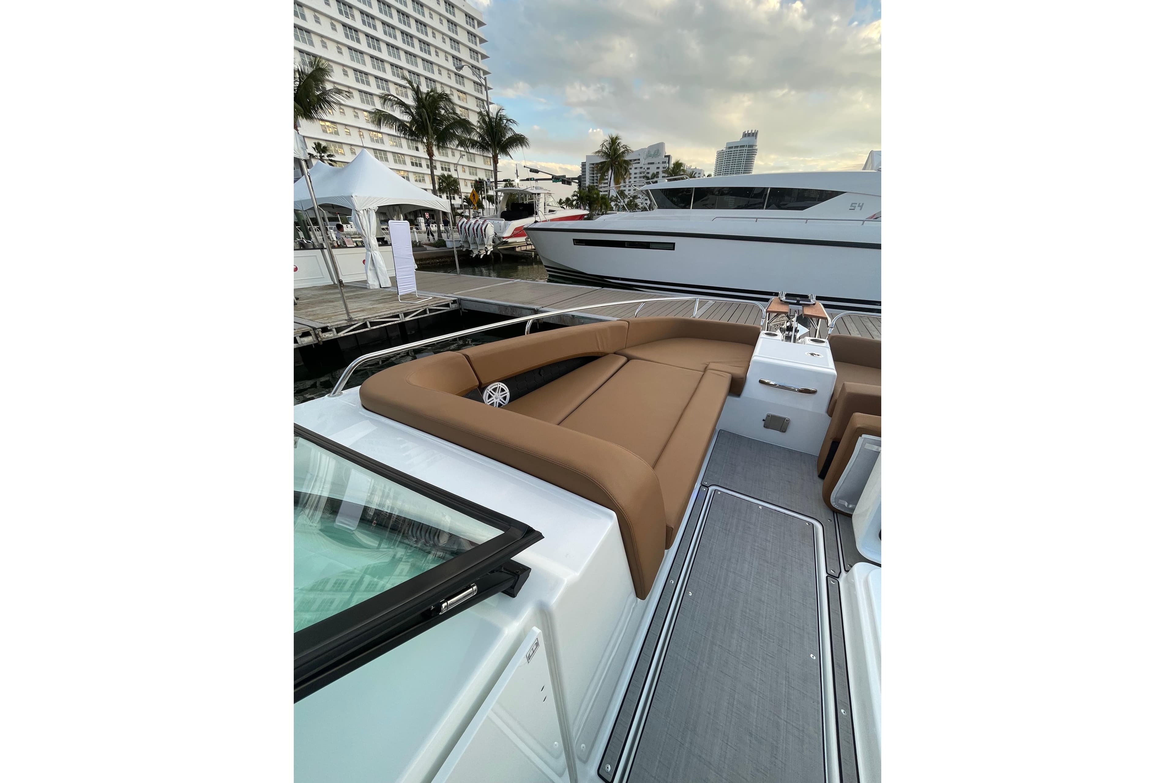 2026 Jeanneau TH33 yacht with luxurious seating at a marina, showcasing modern design.
