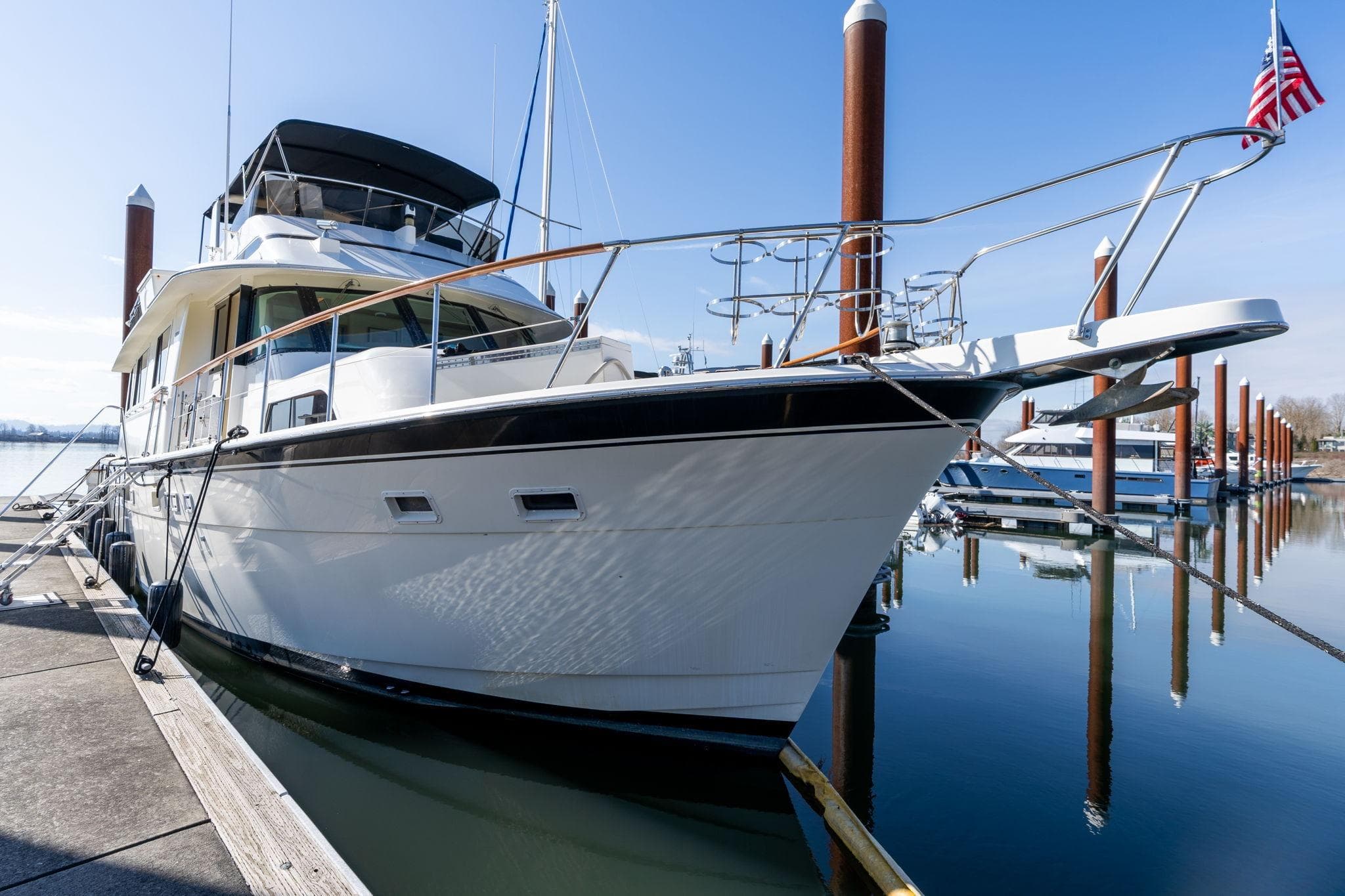 1986 Hatteras 63 Motor Yacht docked at marina, clear sky, calm water.