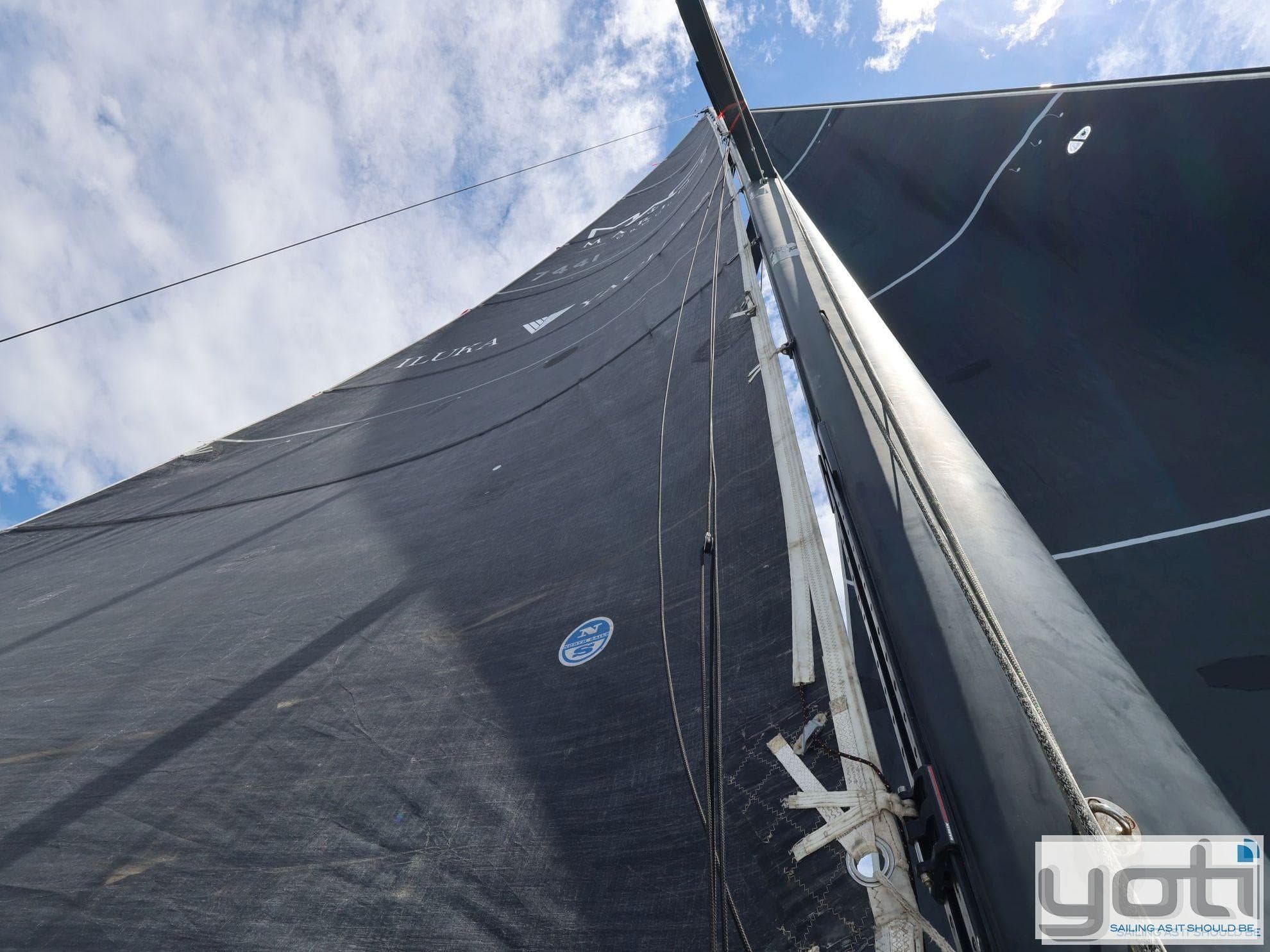 Sail of a 1999 Custom Murray Burns Dovell 62 yacht against a blue sky.