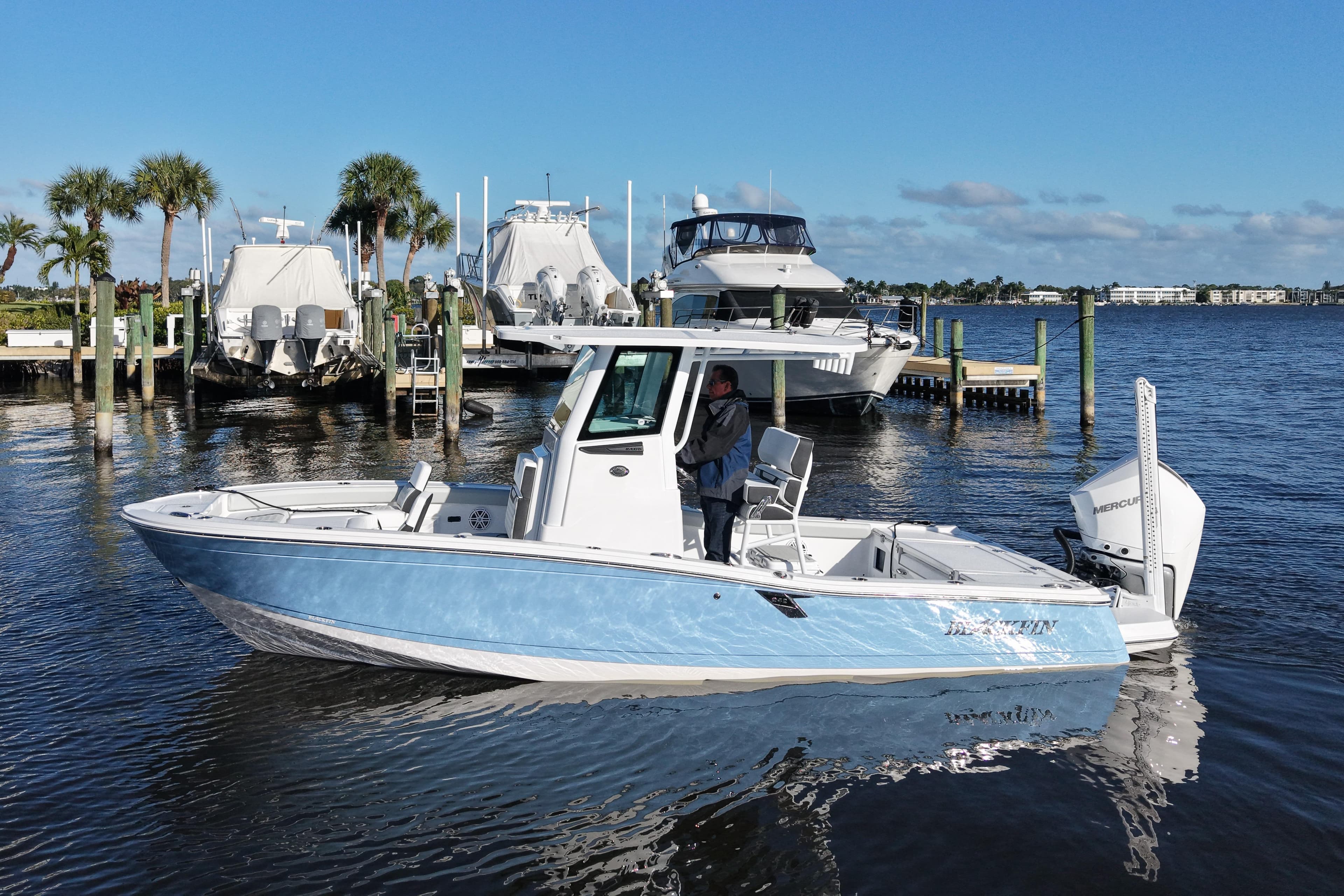 2026 Blackfin 242 HB boat docked in a marina with palm trees and yachts.