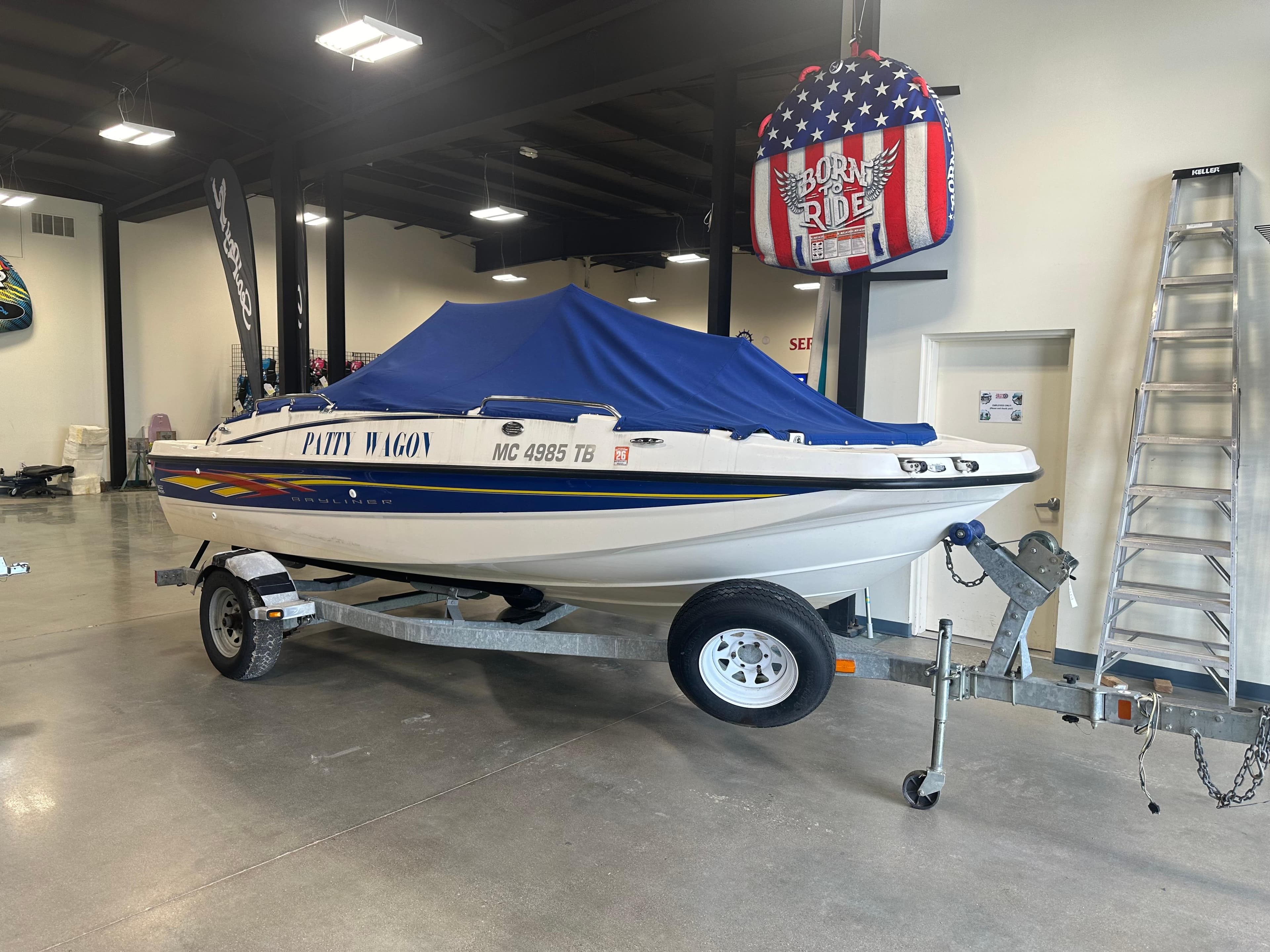 2007 Bayliner 197 boat with blue cover on trailer in showroom.