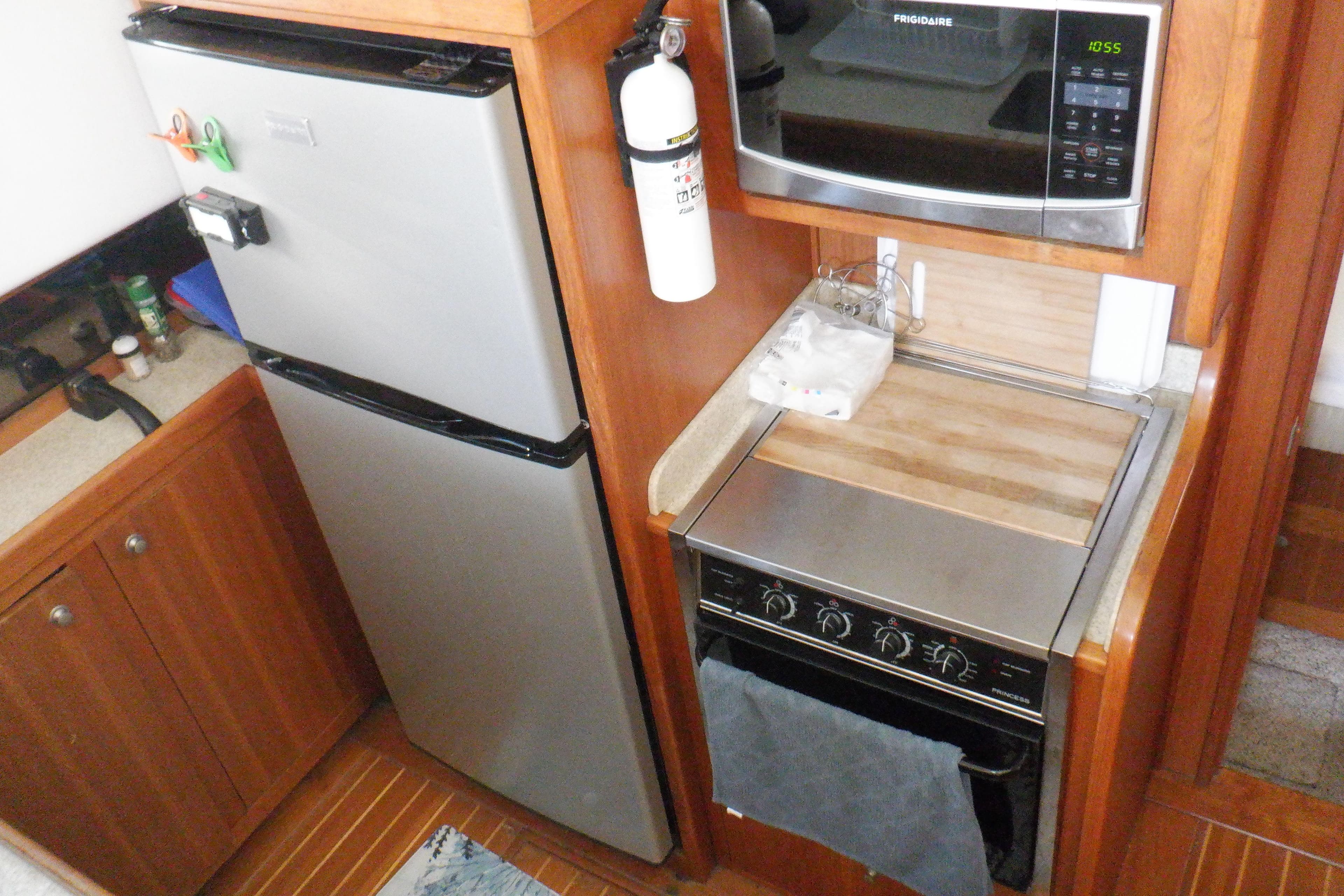 2002 Mainship 430 Trawler kitchen with fridge, microwave, and stove in compact layout.