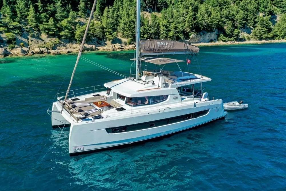 2022 Bali 4.6 catamaran sailing in clear blue waters near a forested coastline.